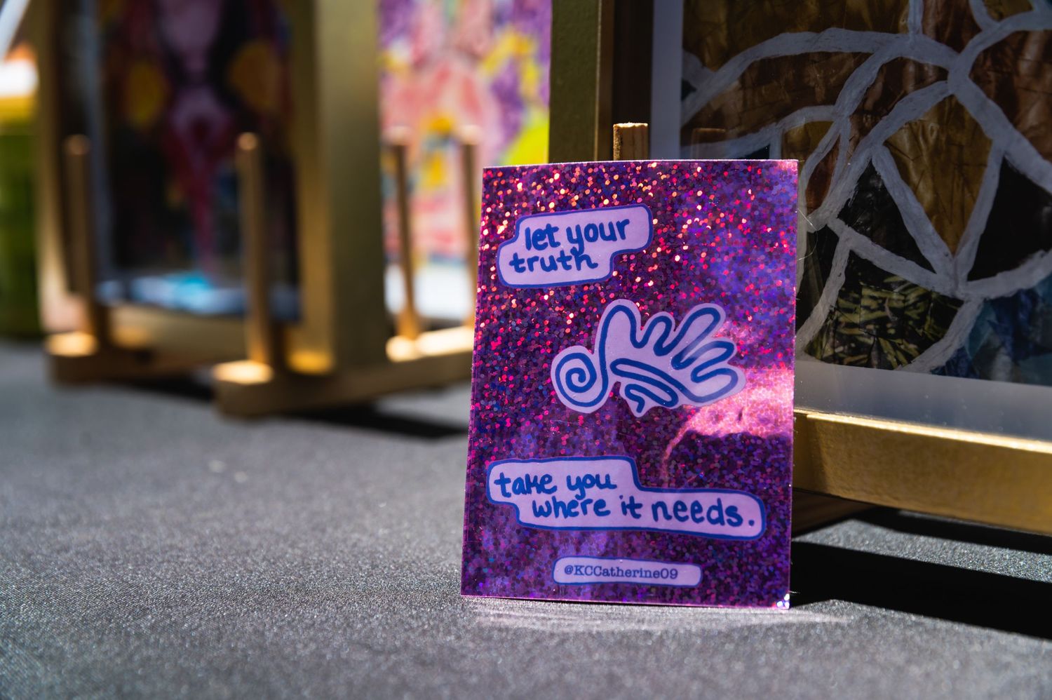 A purple artistic sign with white text displayed in a dim lit hallway.