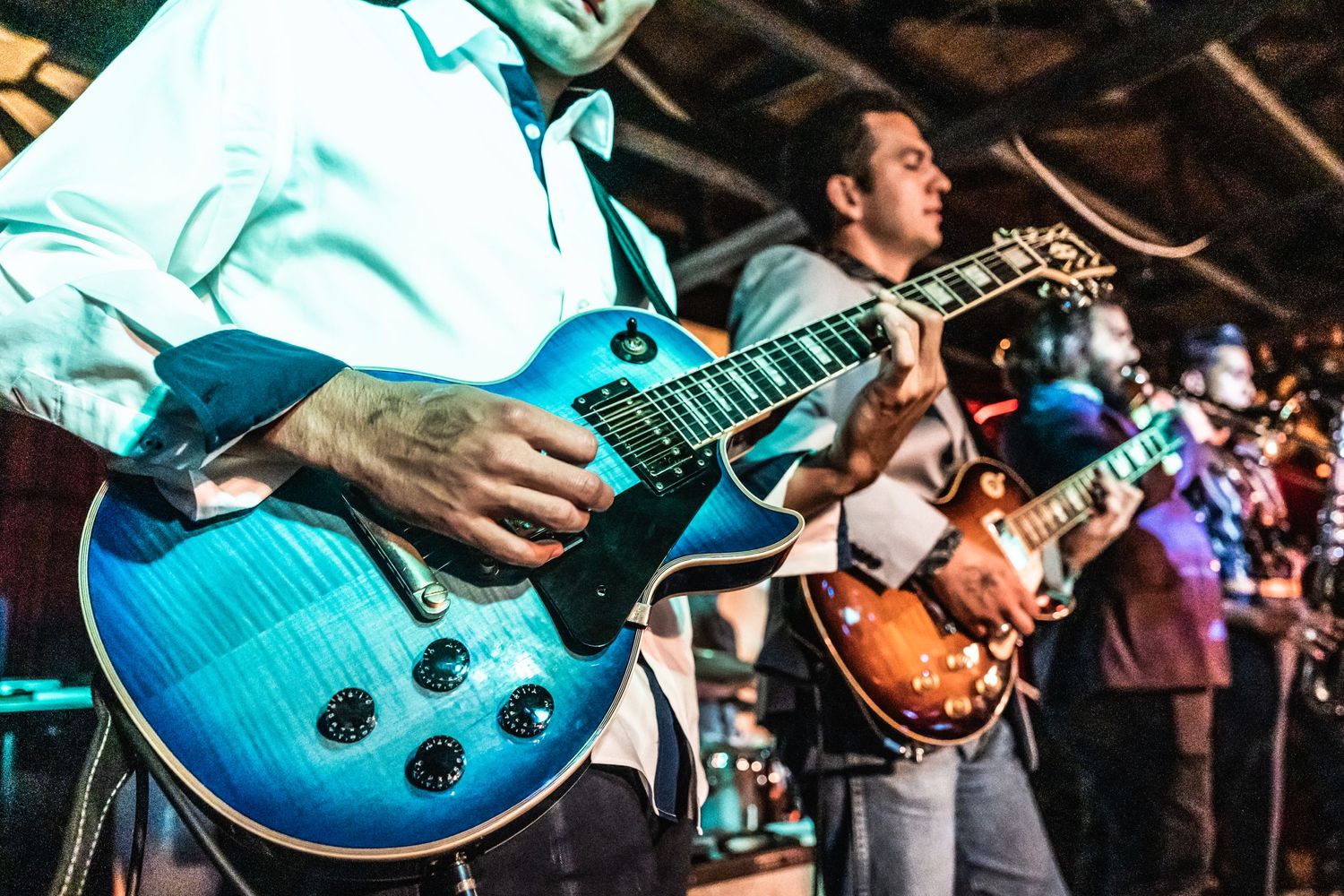 Musician playing blue electric guitar on stage during live performance.