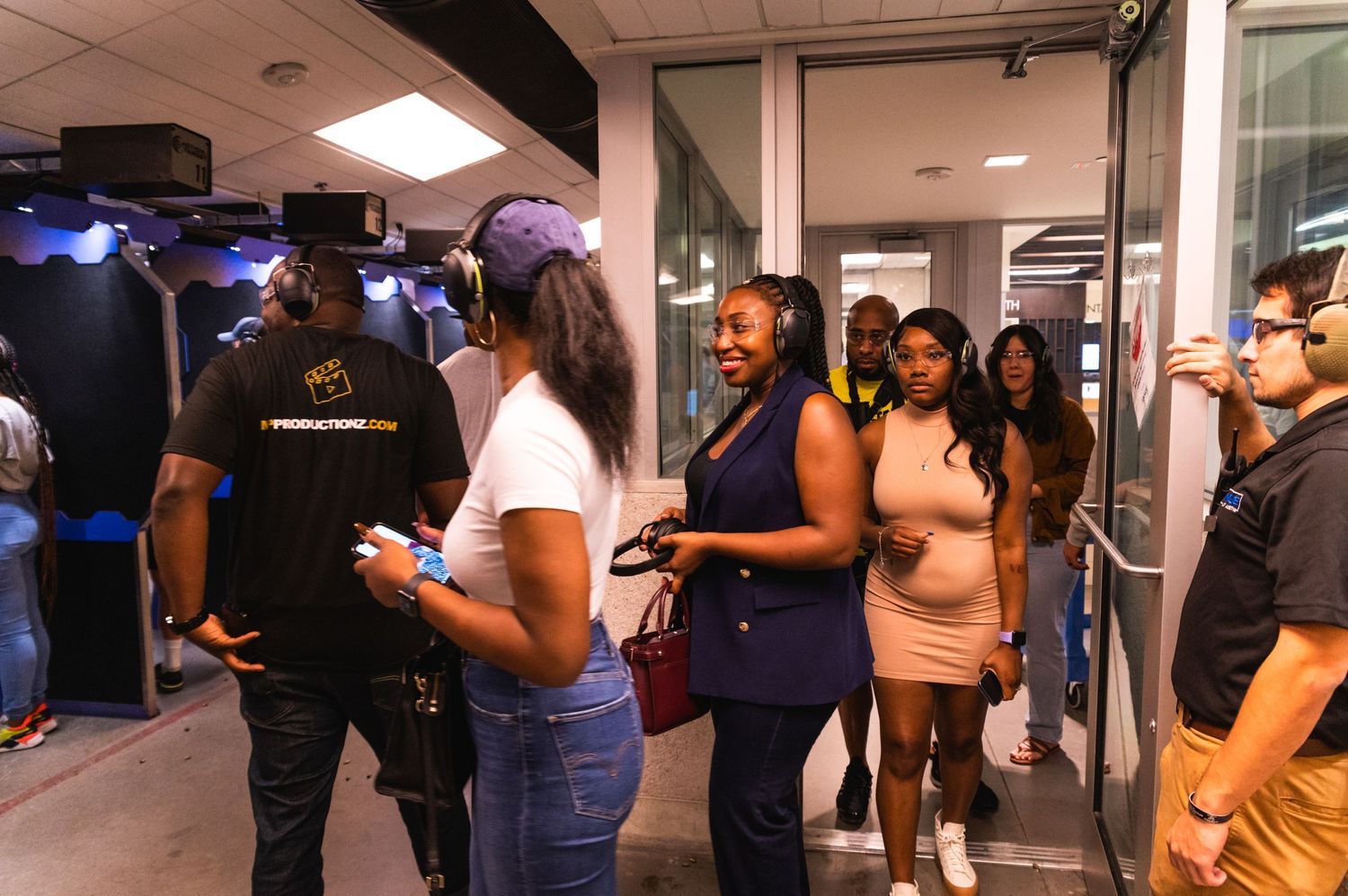Group of people standing in line in a hallway with blue lighting.