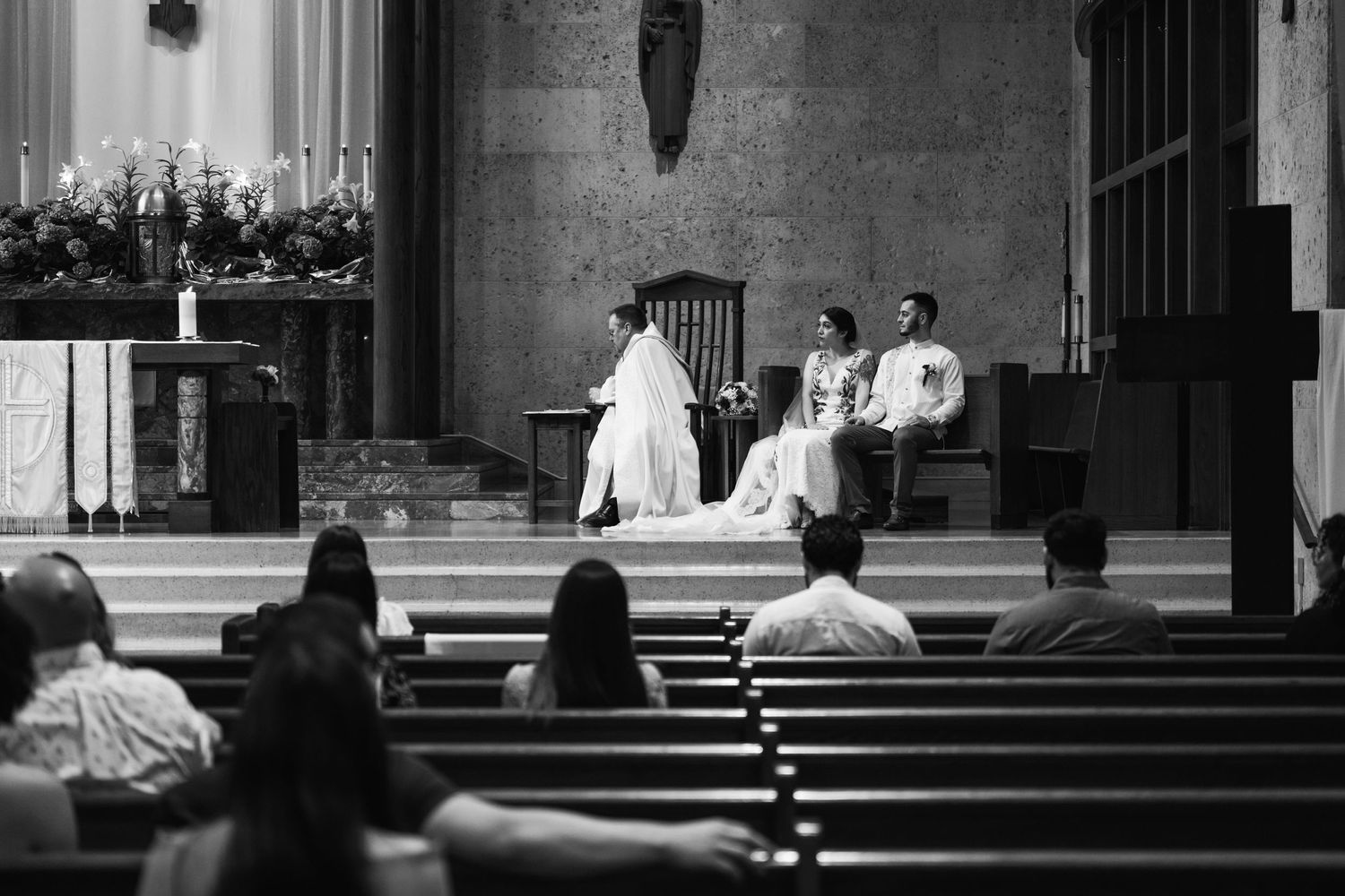 Black and white photo of a church wedding ceremony with guests seated in wooden pews.