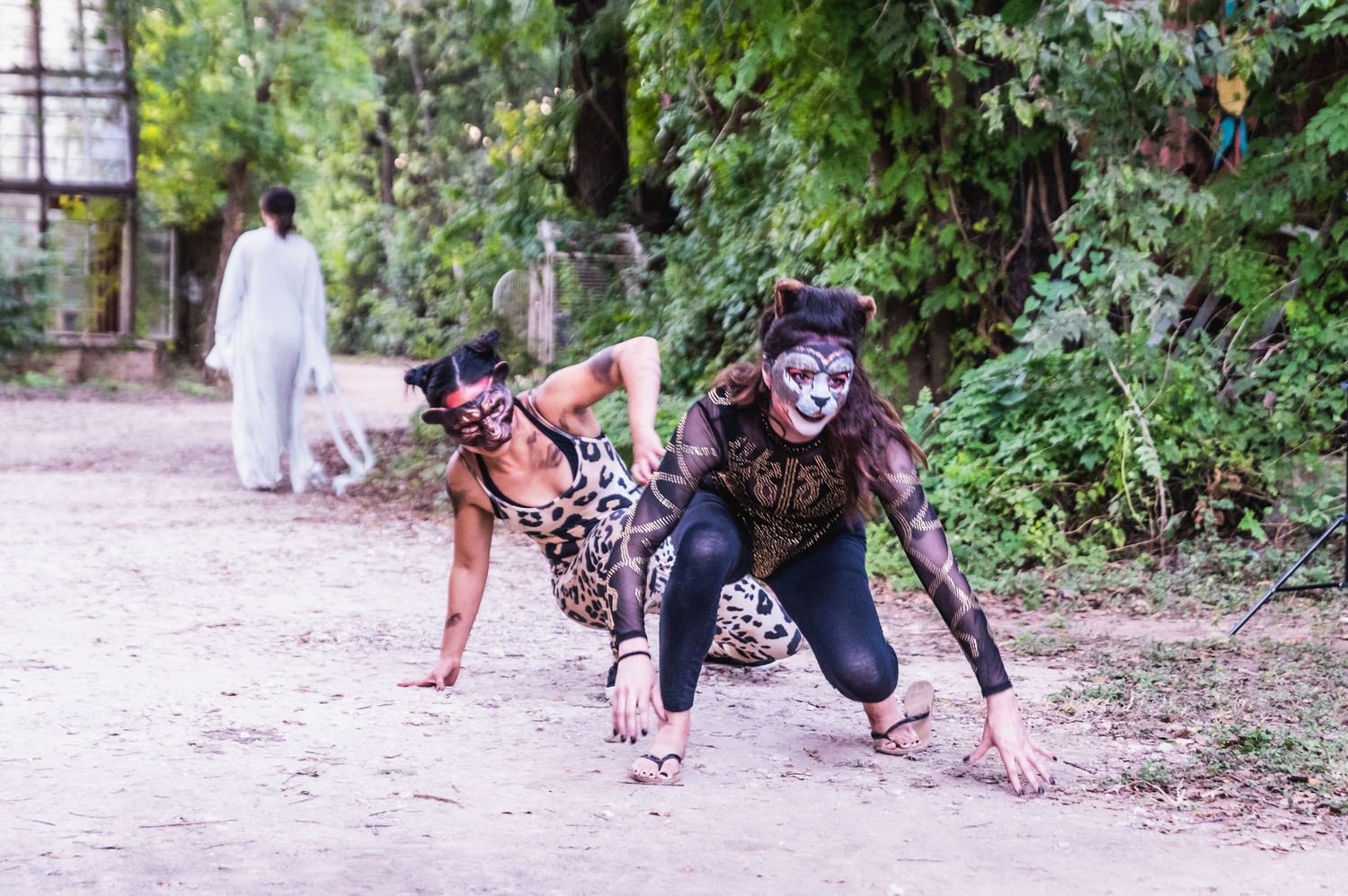 Costumed performers in dramatic makeup pose on forest path.