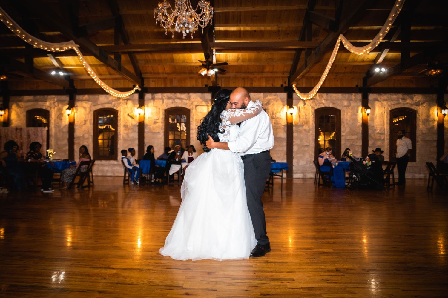 A romantic dance scene unfolds on a polished wooden floor under elegant draping and warm lighting.