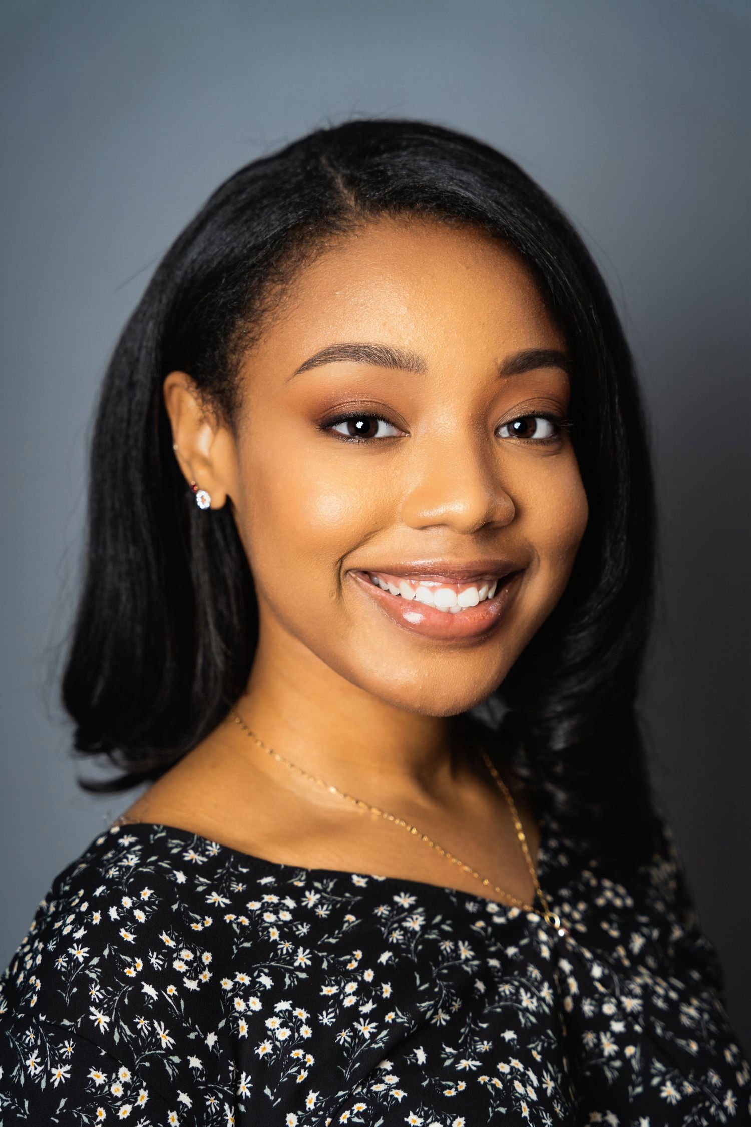Professional studio headshot with soft lighting against gray background.