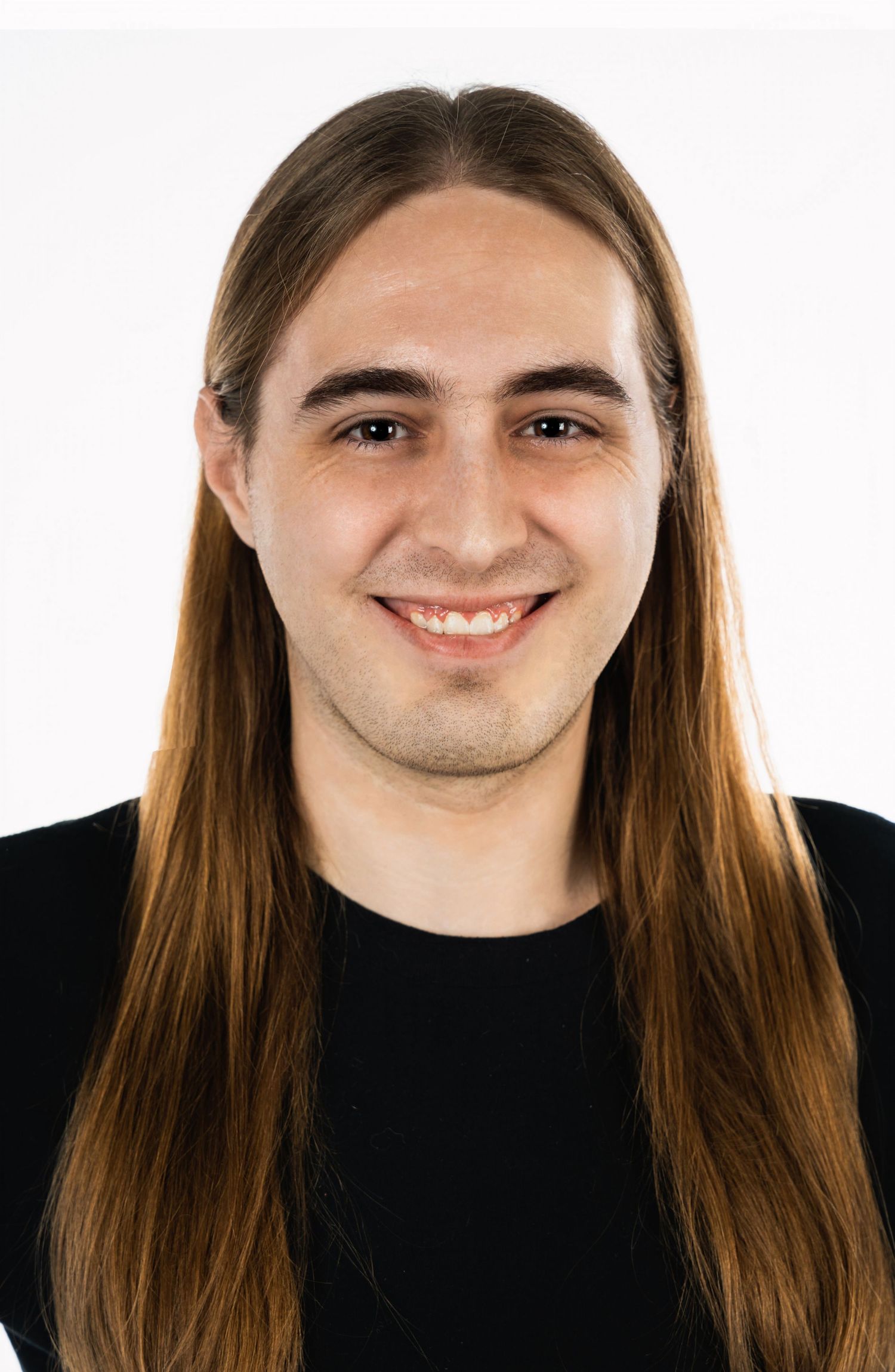 Portrait of person with long brown hair wearing black shirt against white background.