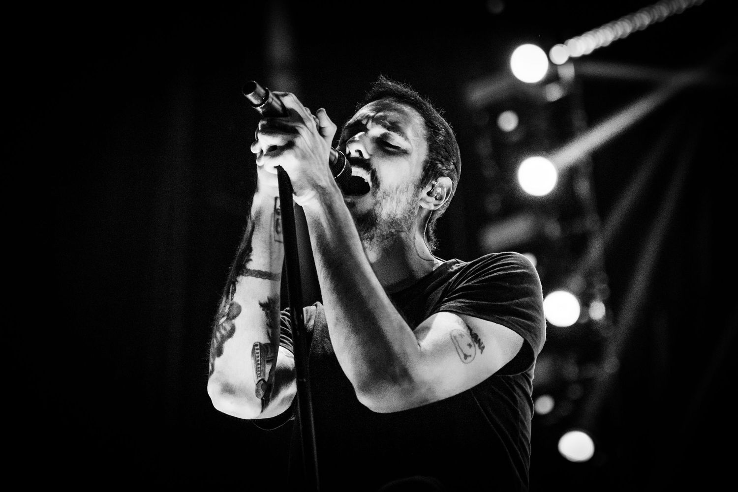 Black and white concert performance photo showing a singer passionately performing on stage with dramatic lighting.