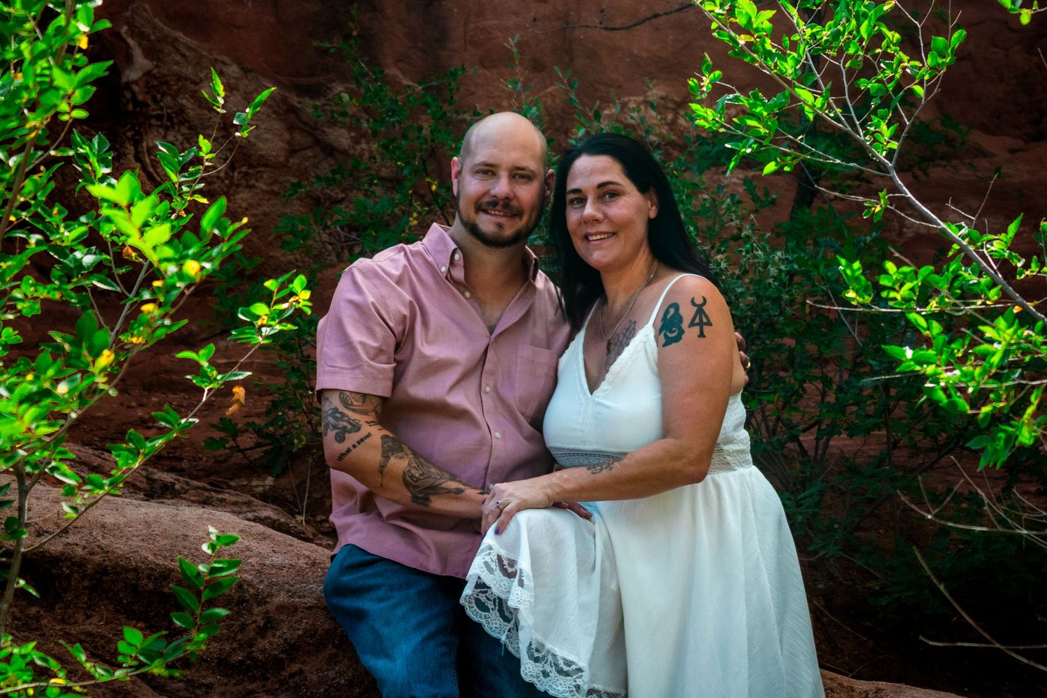 Five candid shots show a couple embracing at an outdoor photo session with vibrant green foliage and red rocks in background.