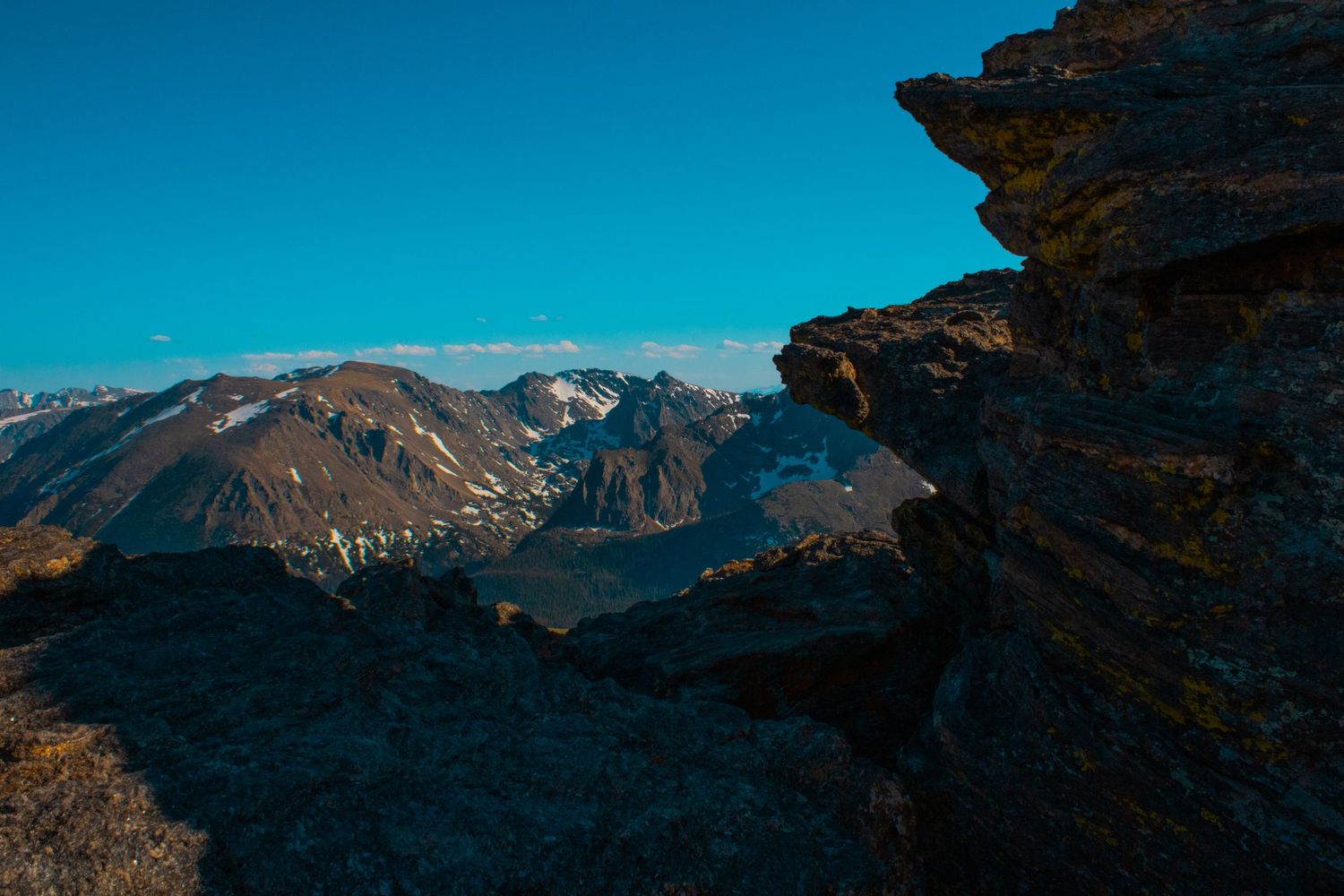 Dramatic mountain silhouettes and jagged peaks outlined against a bright turquoise sky.