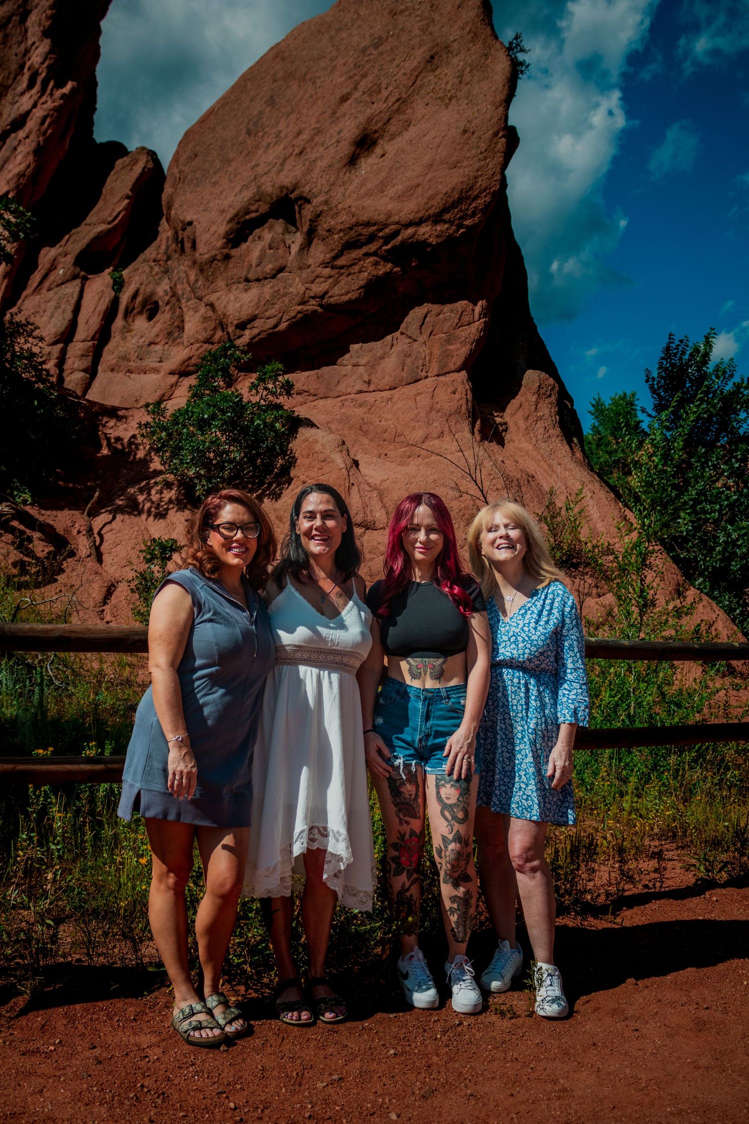 A group poses in front of red rock formations with dramatic blue skies at Garden of the Gods in Colorado.