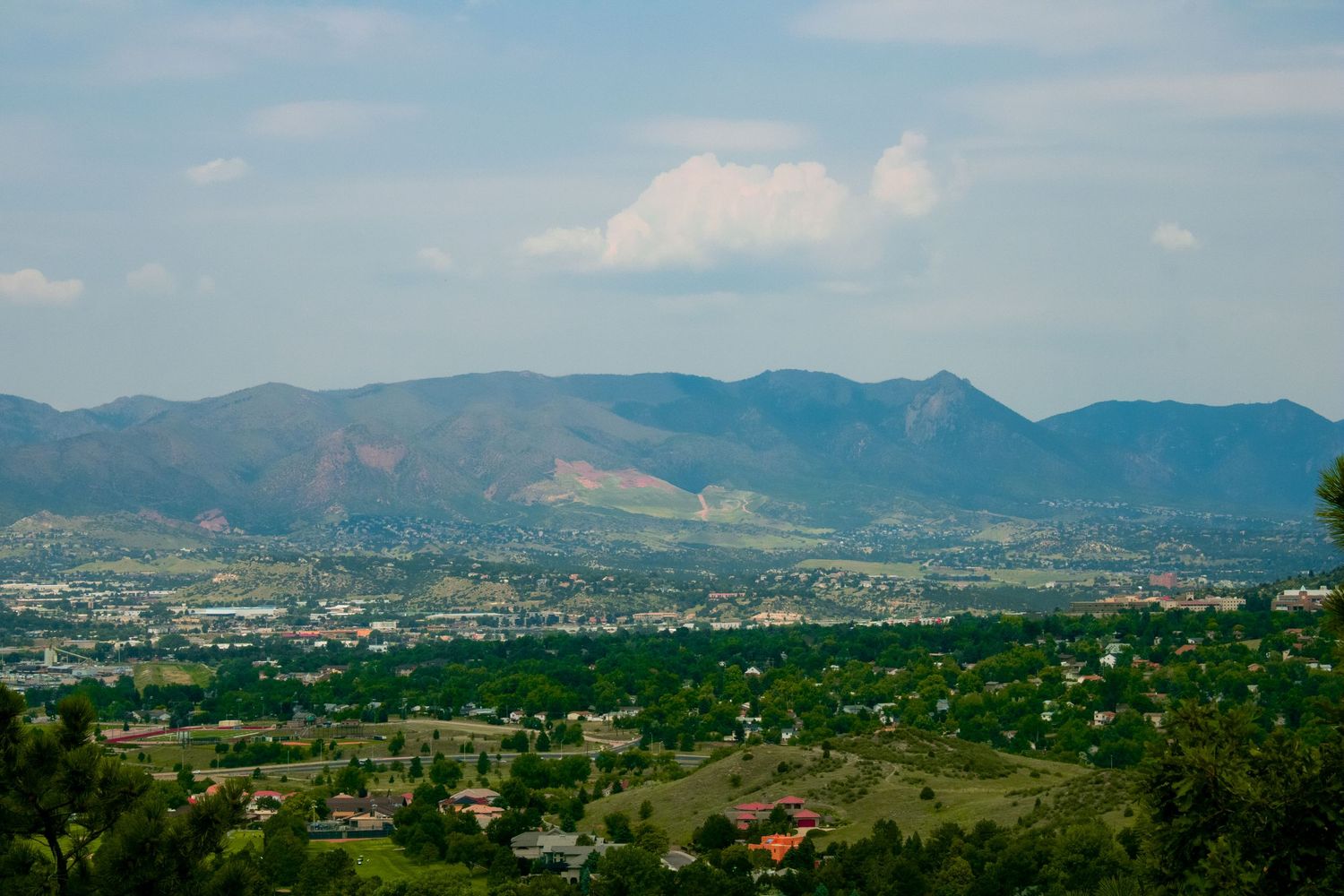 Scenic mountain range overlooking a sprawling valley with suburban development in the distance.