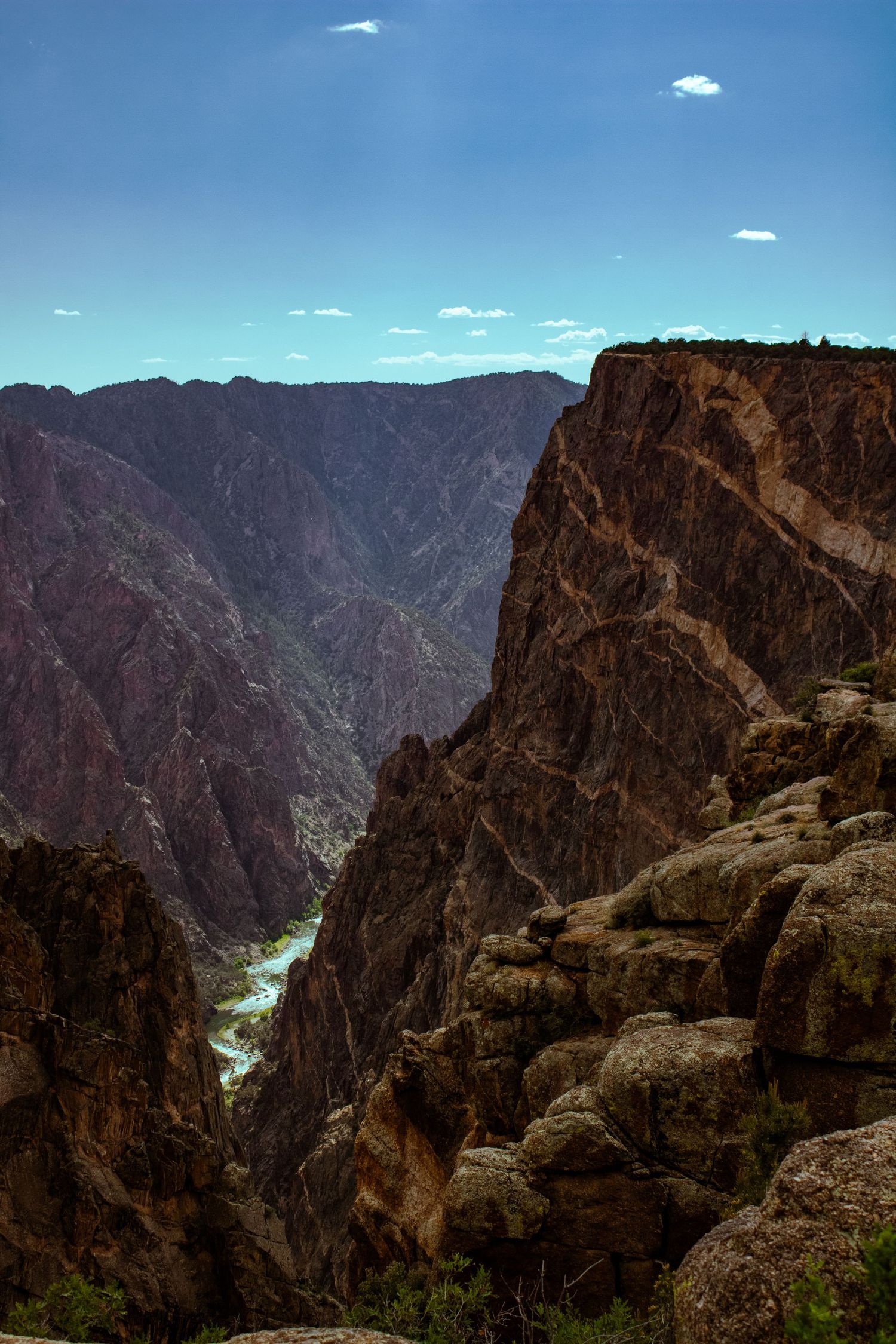 Rocky overlook provides stunning view down into Black Canyon's deep gorge with river visible far below.