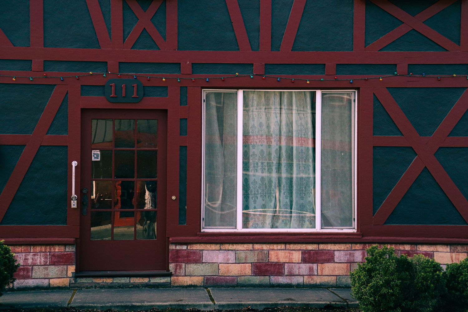 Modern building exterior with red timber framing and white windows.