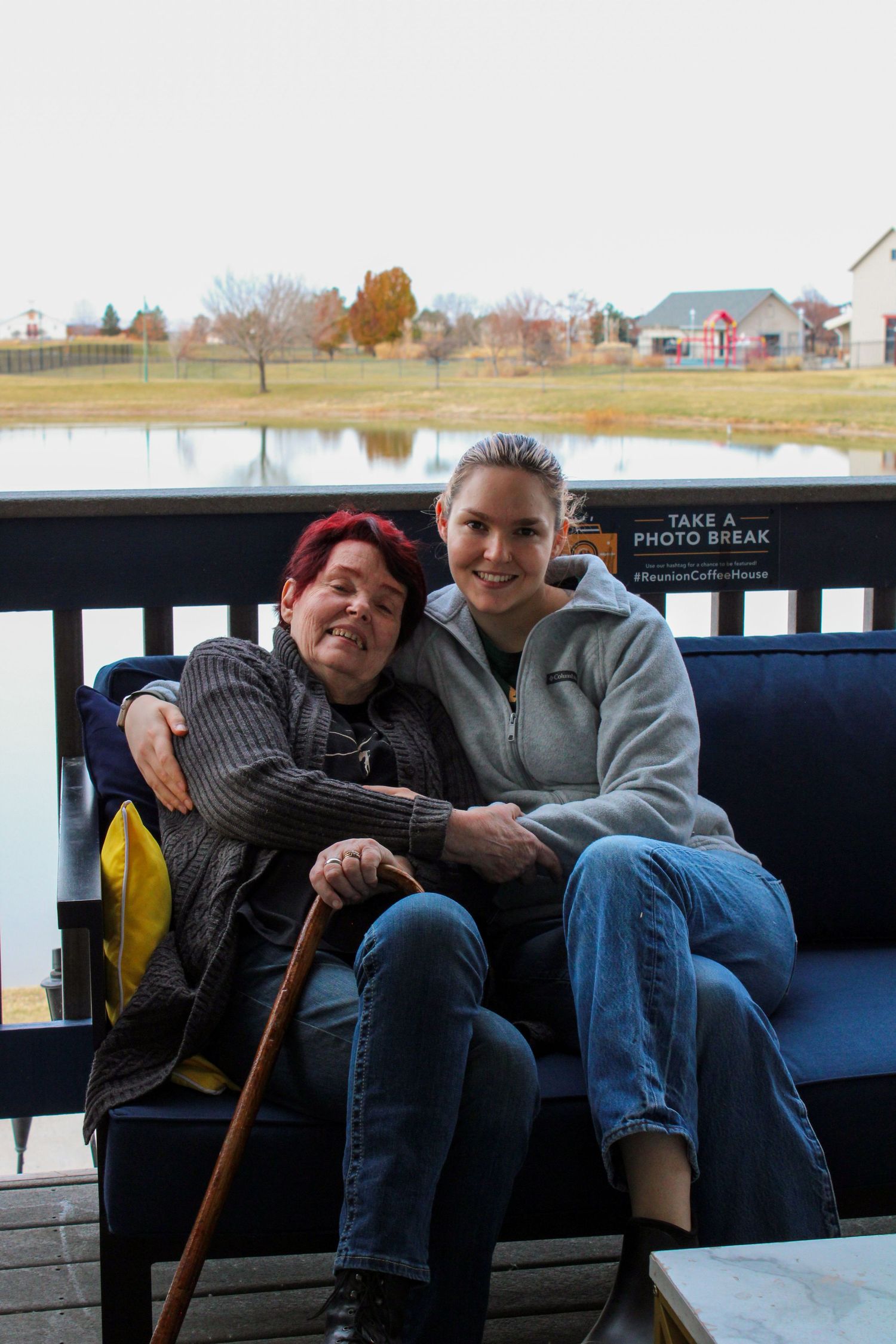 People sitting together on a blue bench by a waterfront during daytime.