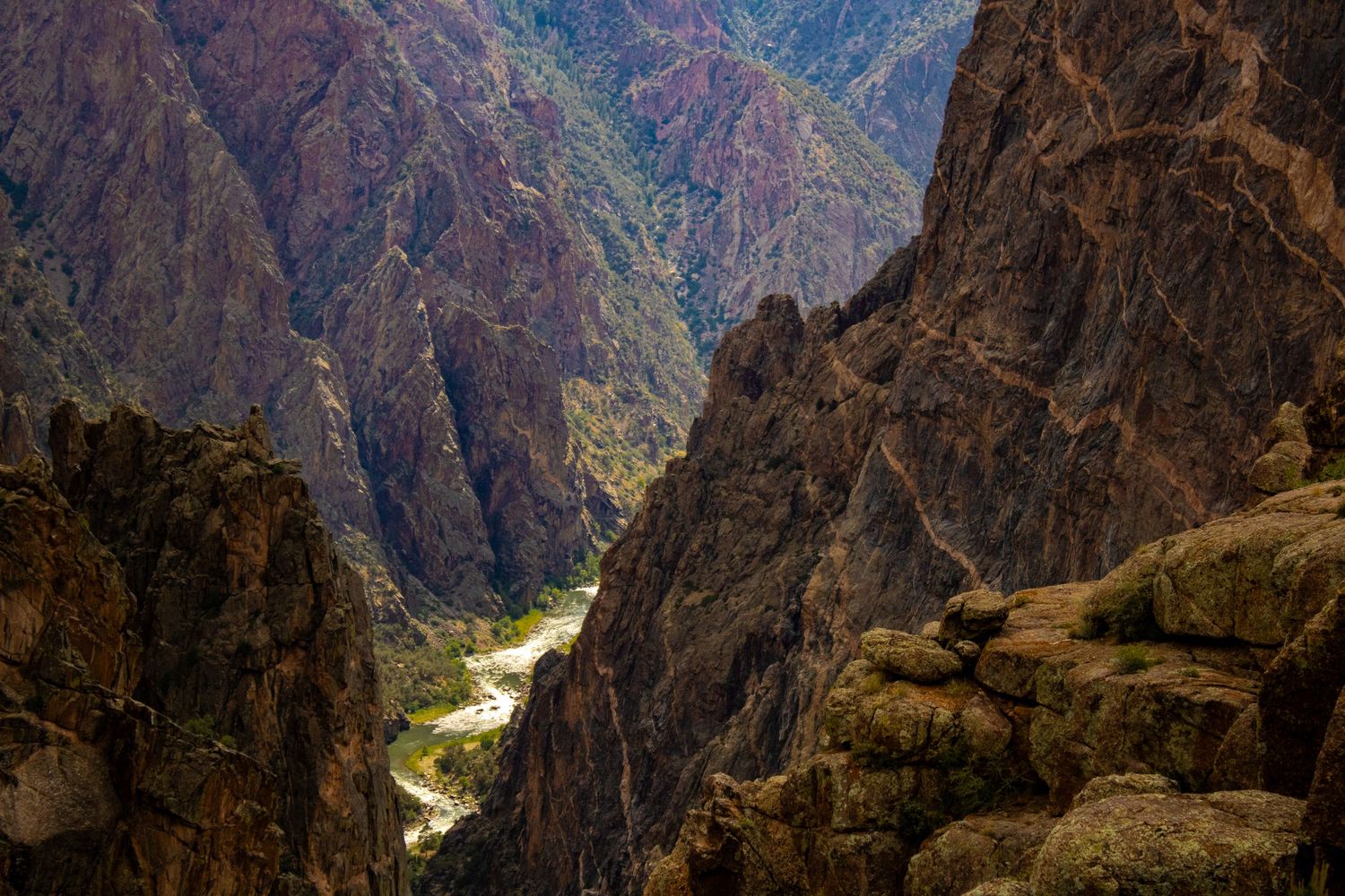 Panoramic view of deep canyon walls with river snaking through rocky terrain.