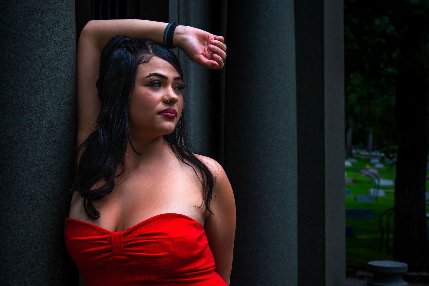 A woman in a striking red dress poses confidently against dark backgrounds in a fashion photography series.