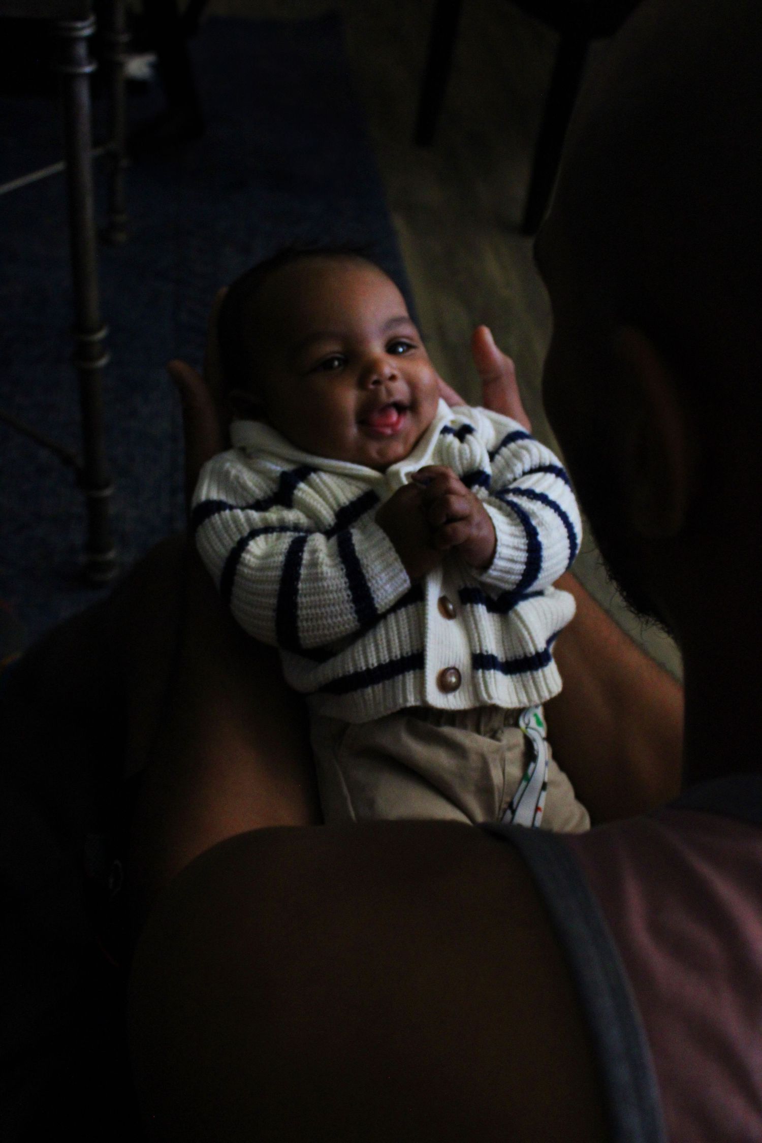 Low-light portrait of a baby wearing a striped outfit.