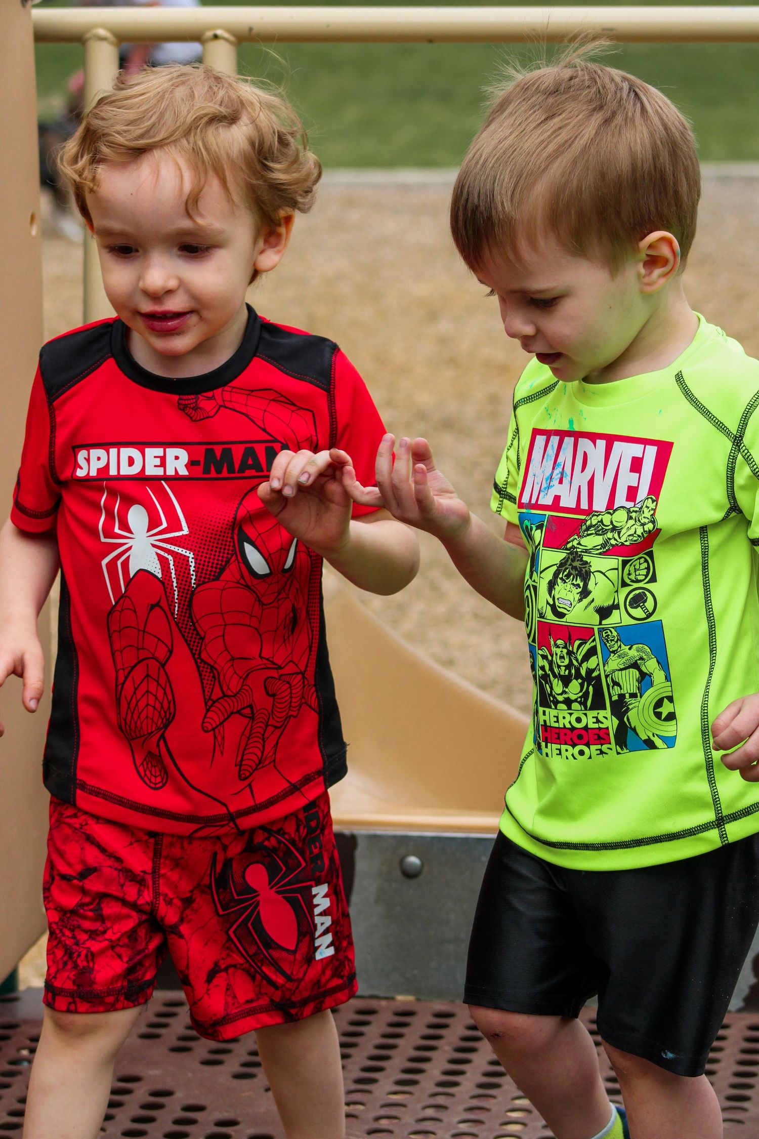 Young children wearing Marvel superhero t-shirts in red and green colors.