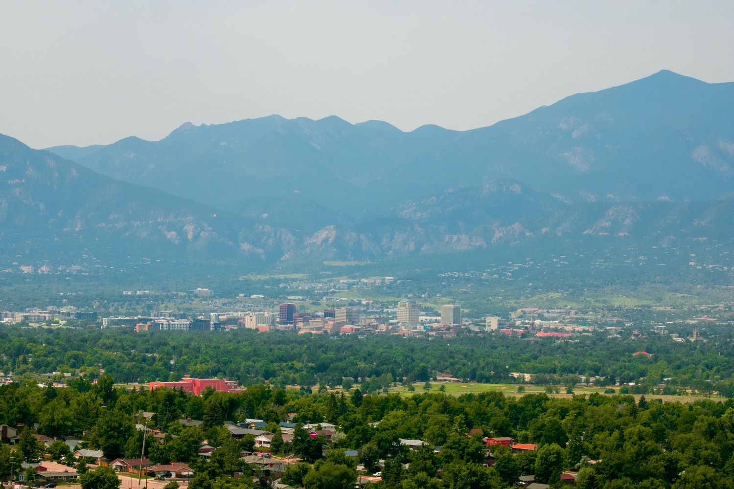 Scenic mountain landscape overlooking an urban area with buildings nestled in greenery.