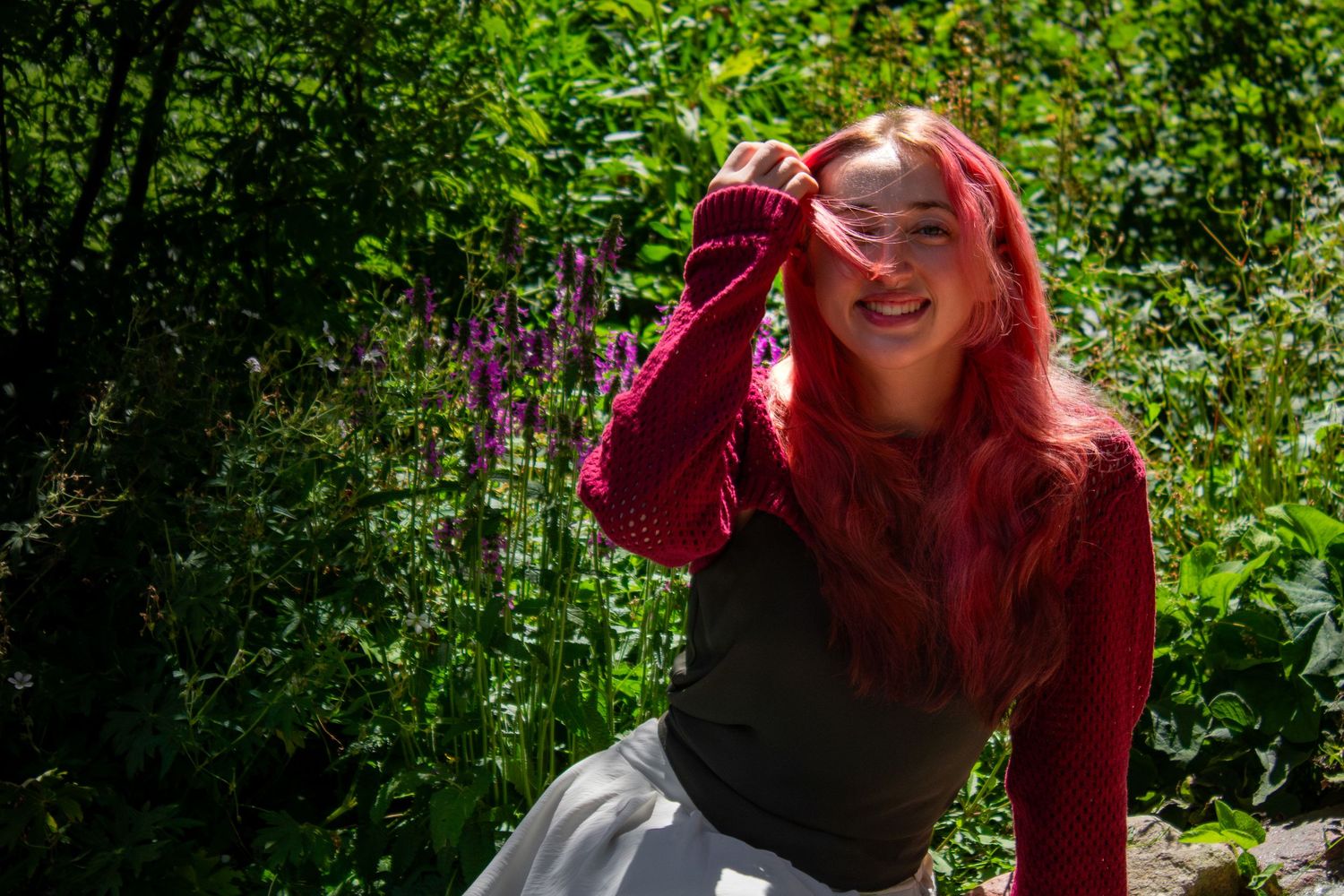 Person with vibrant red hair enjoying a bright summer day outdoors.
