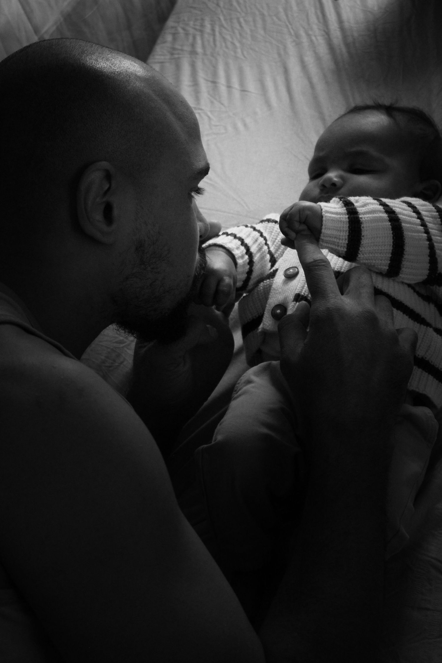Black and white intimate portrait showing tender family moments in low light.