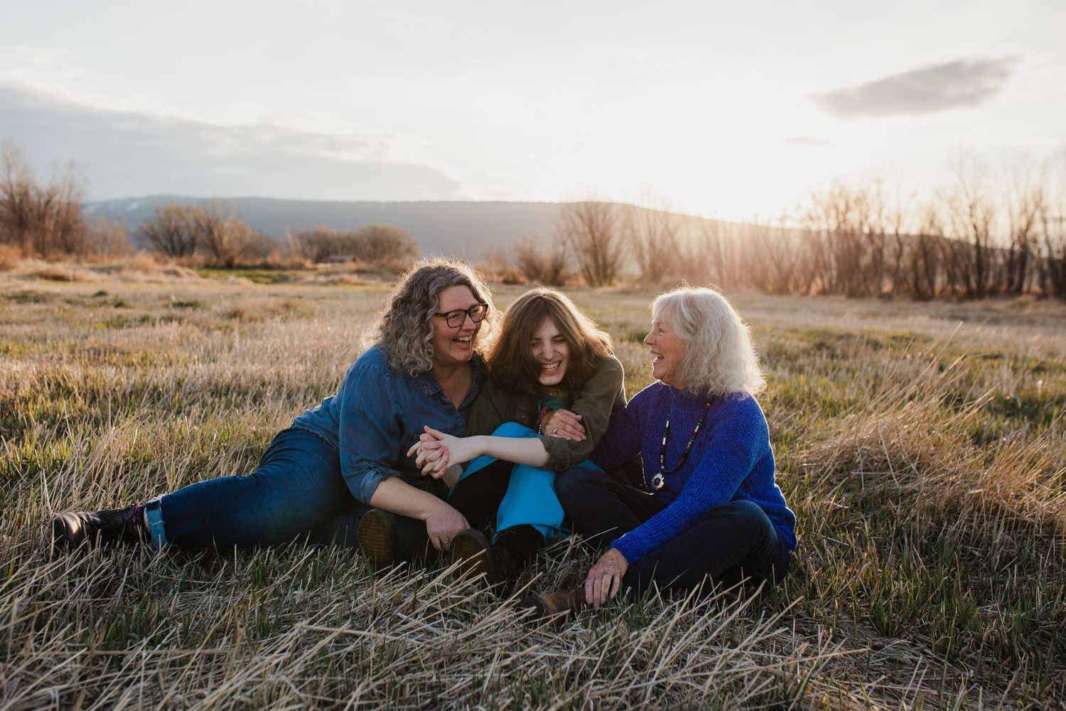 People laying in golden grass at sunset in a natural setting.