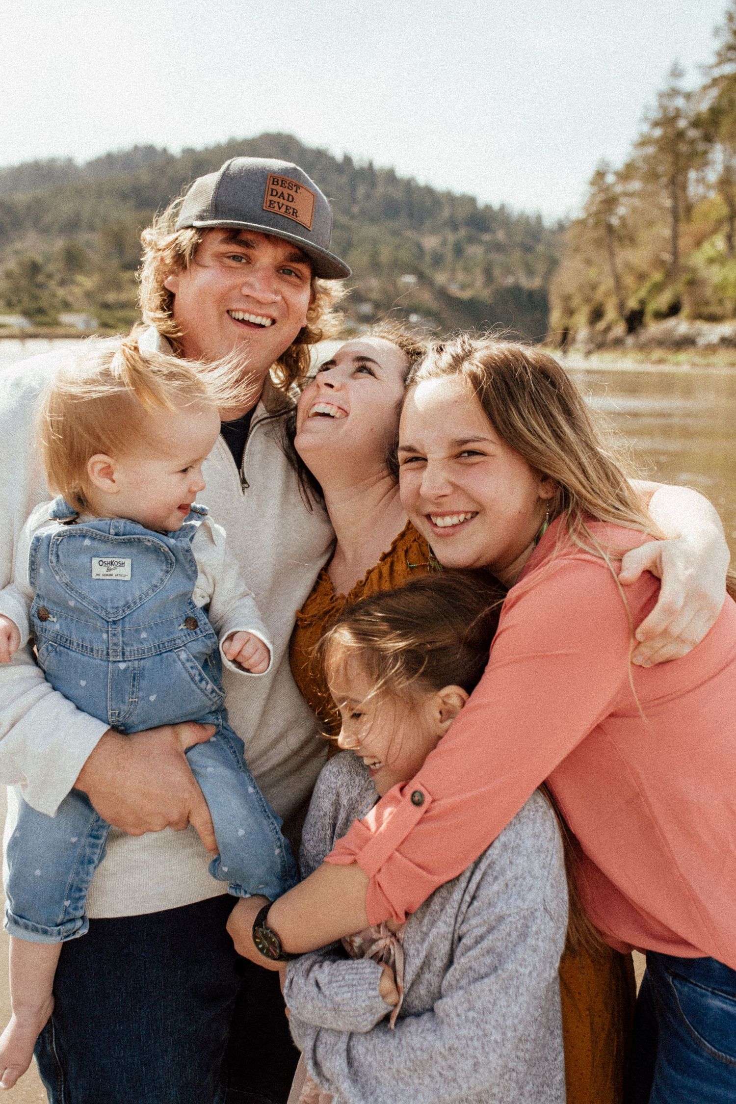 candid outdoor family photos showing joyful moments of laughter and embraces by  the ocean.