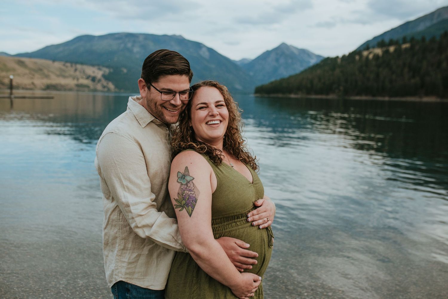 A couple shares tender moments by a serene mountain lake during a romantic lakeside photoshoot.