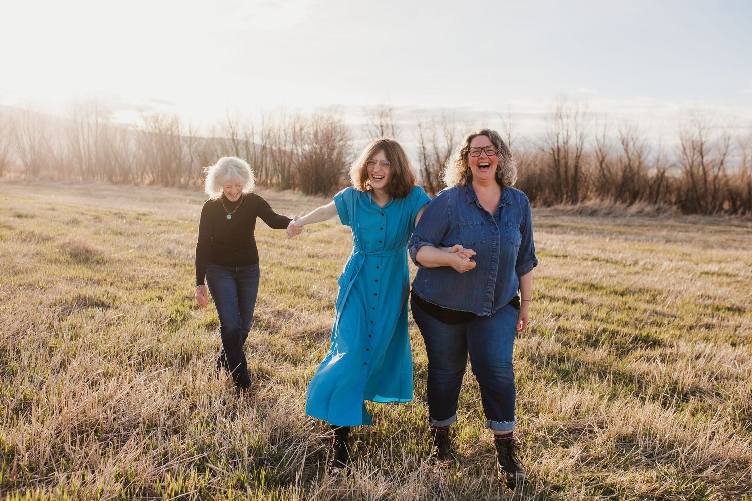 Group together in an autumn field at sunset wearing coordinating blue outfits during a warm outdoor photo session.
