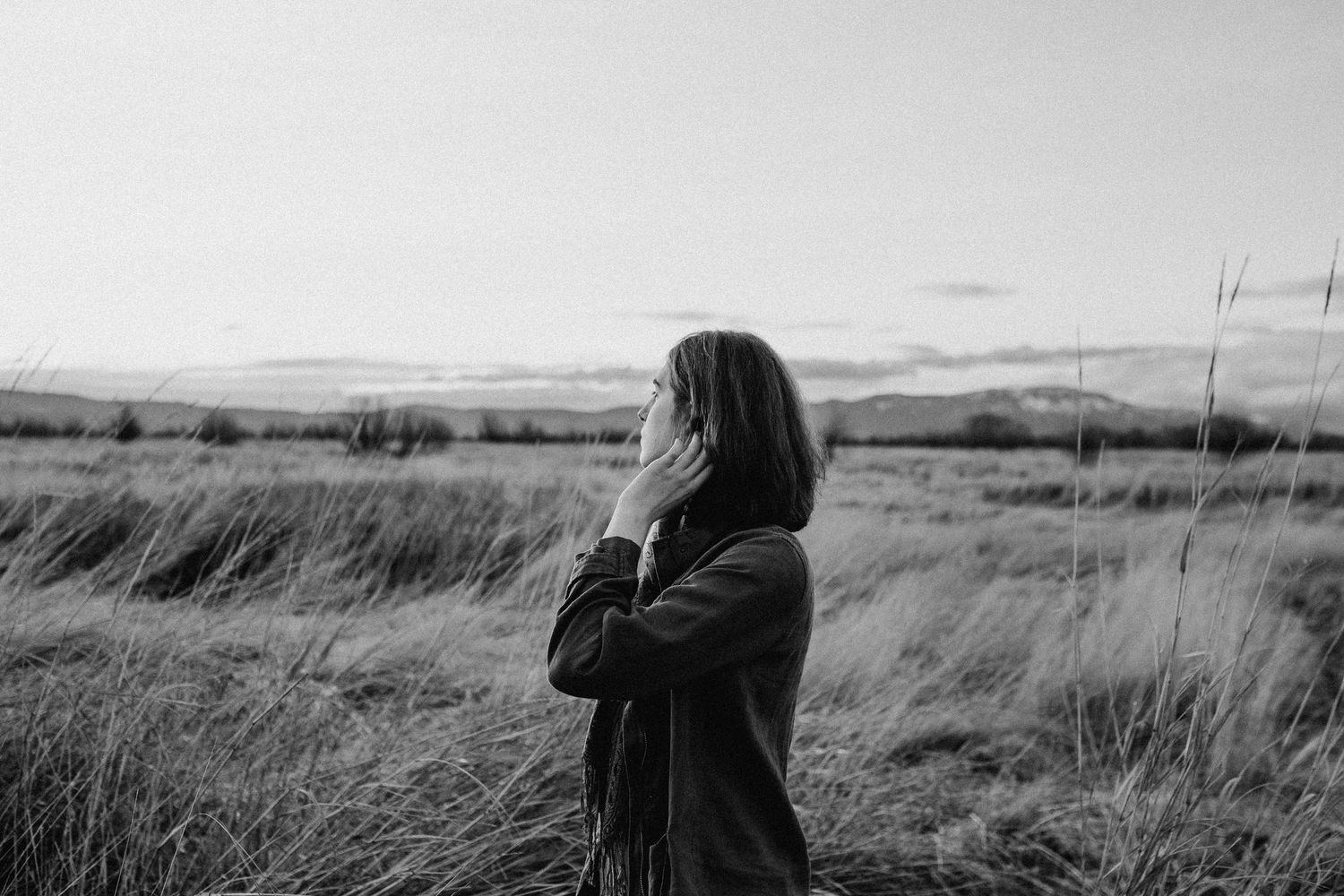 A person looks at a vast prairie landscape with grasses swaying in the wind.