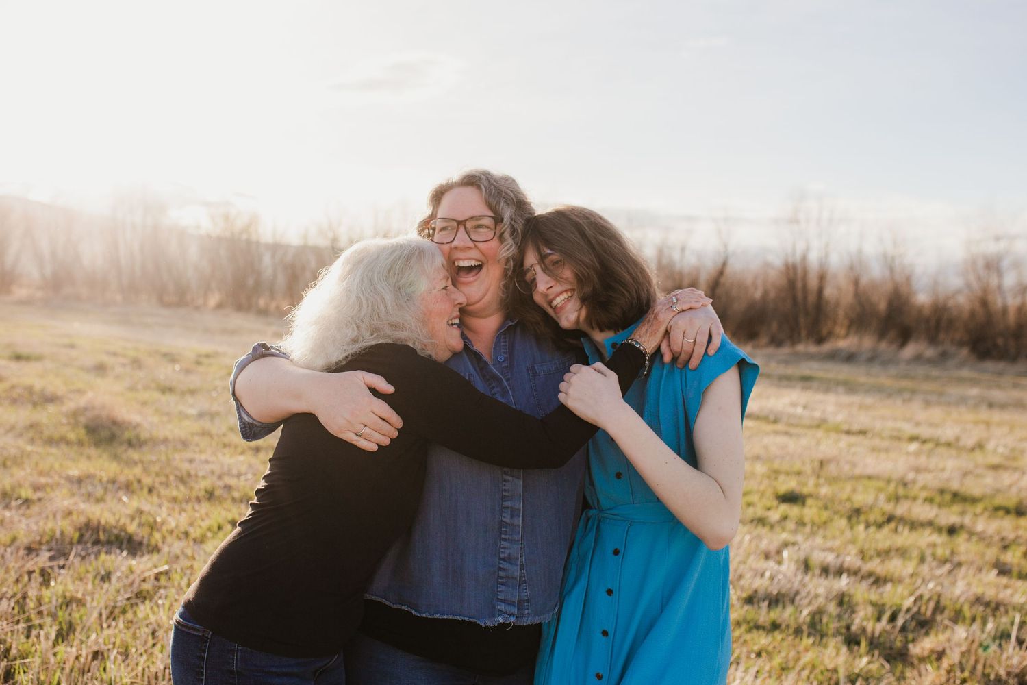 A joyful moment shared between loved ones during an outdoor photo session in a golden sunlit field.