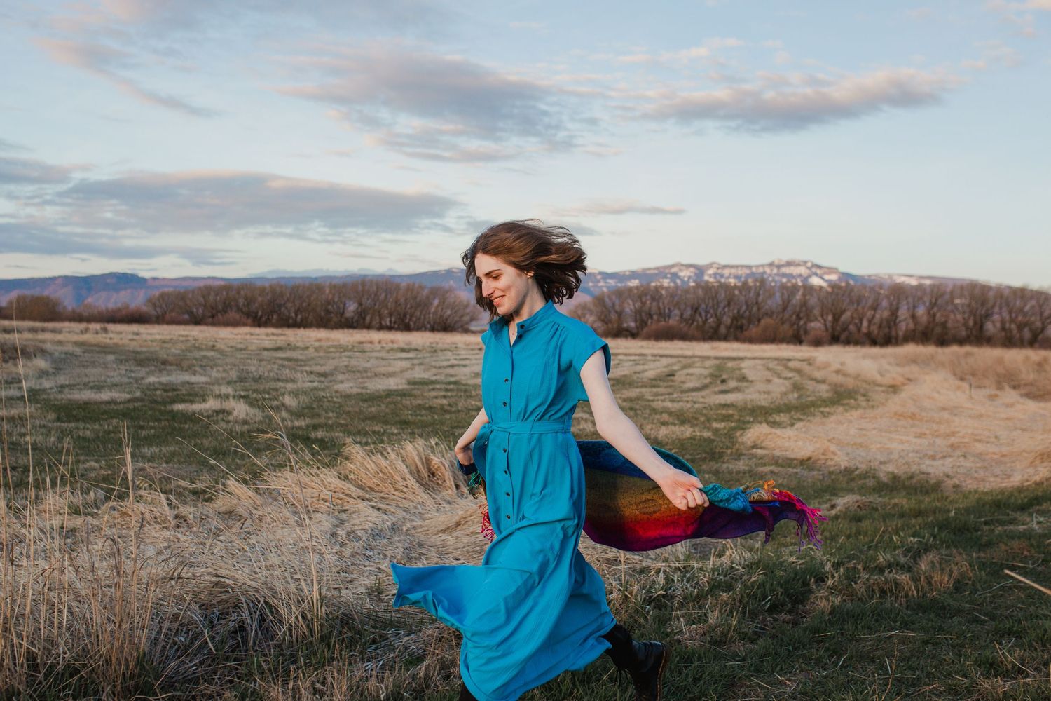 A person in a turquoise dress spins joyfully.