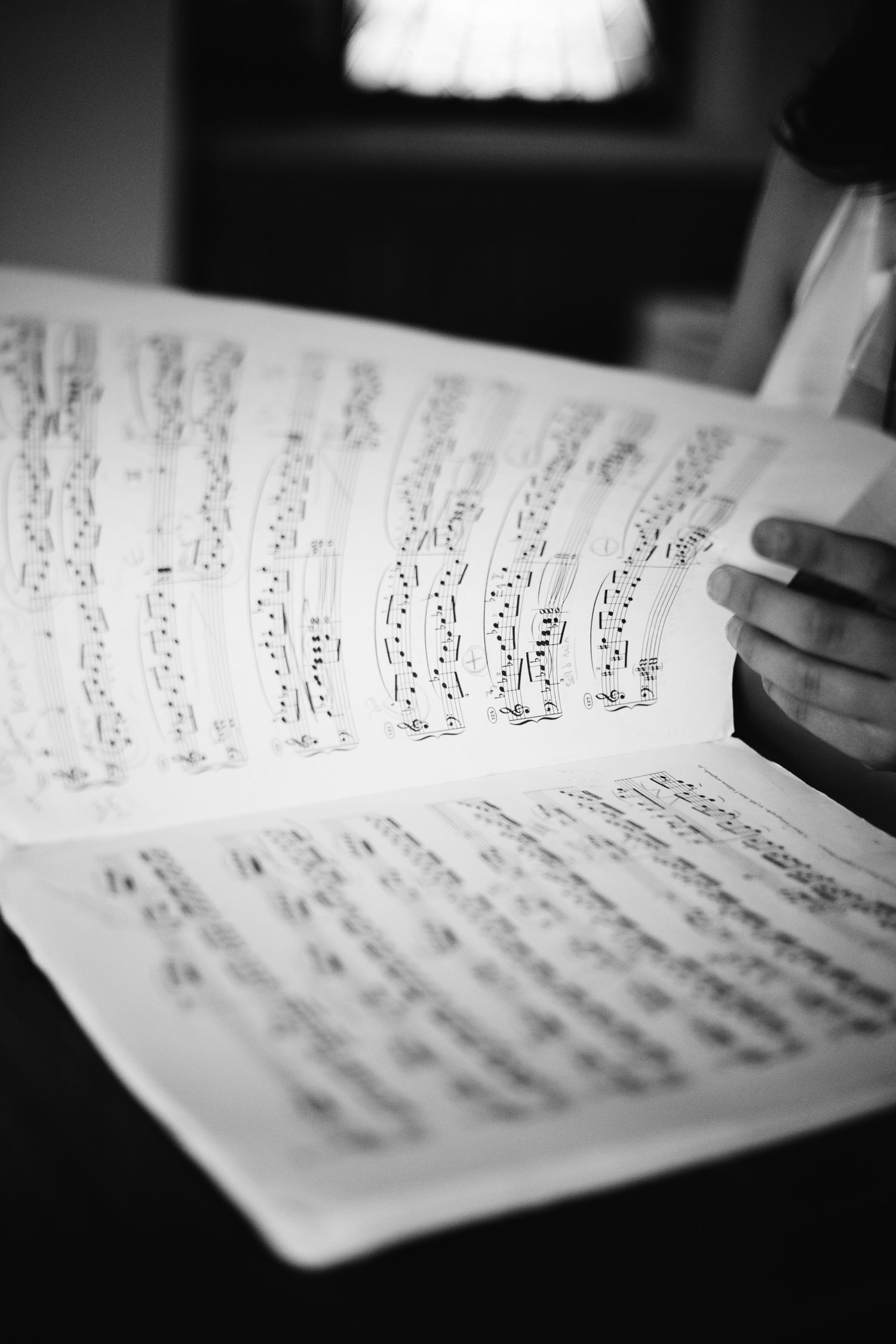 Black and white photo of a musician reading sheet music, holding pages of musical notation.