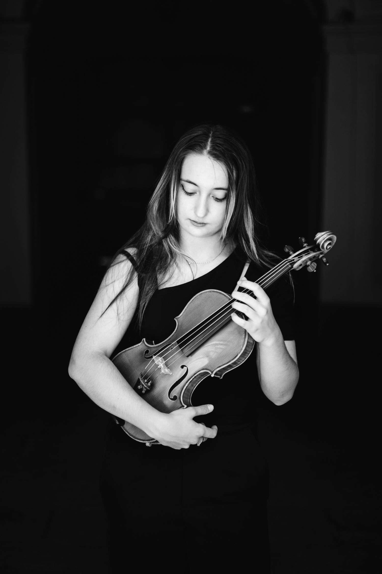 Black and white portrait of a young woman in black dress holding a violin.