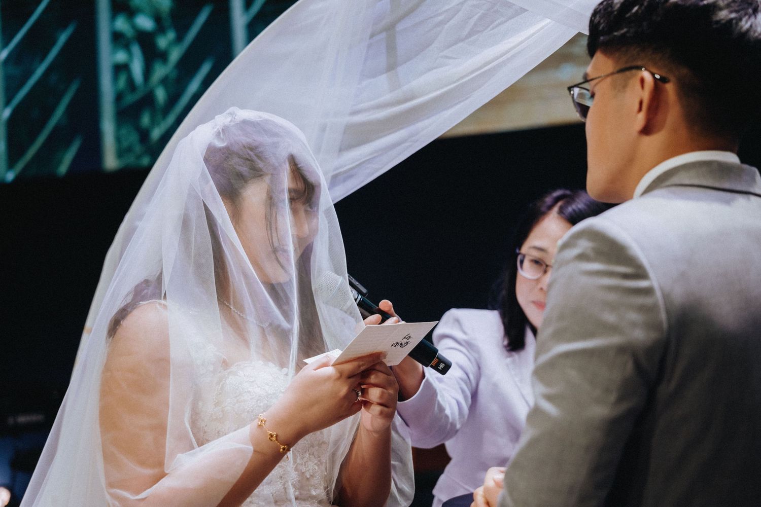 Intimate wedding ceremony moment captured with flowing white veil in focus.