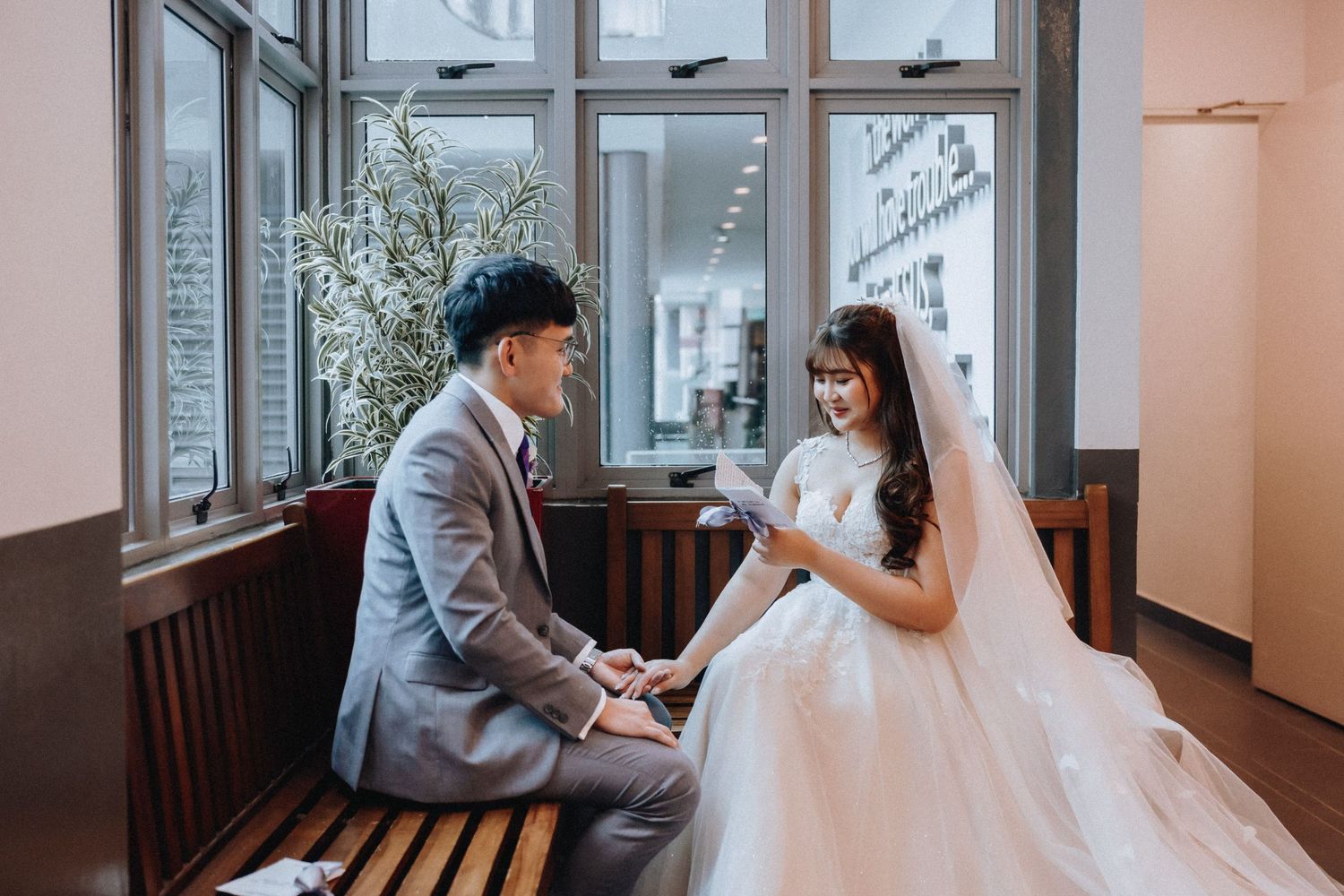 Couple sharing intimate moment on wooden bench in bright indoor setting.