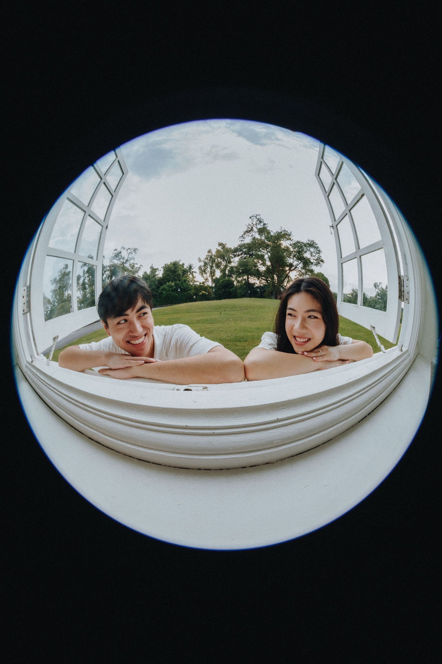 A creative fisheye lens photo showing a couple leaning into the curved frame outdoors.