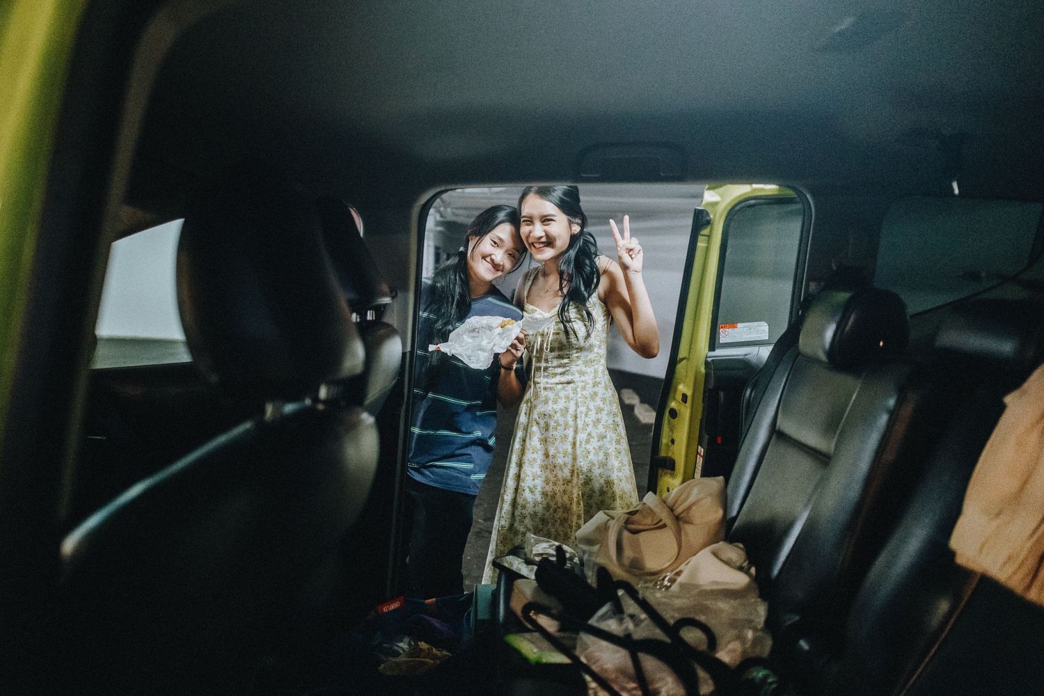 Interior car shot of passengers with luggage and bags in the back seat.