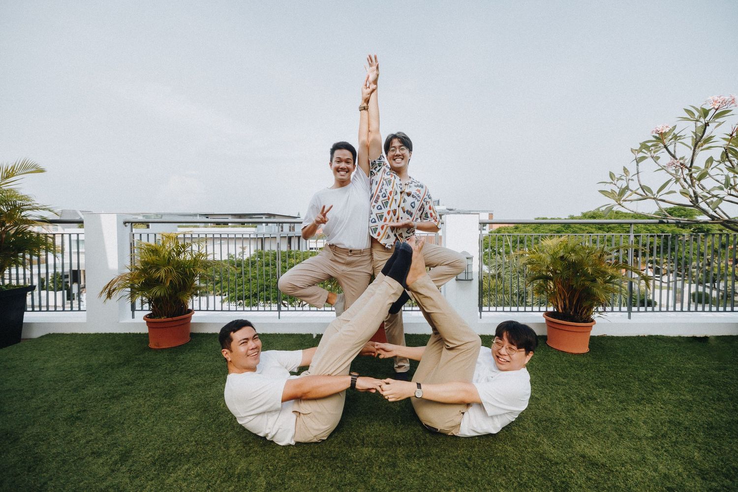 A family poses in a creative pyramid formation on a rooftop garden patio.