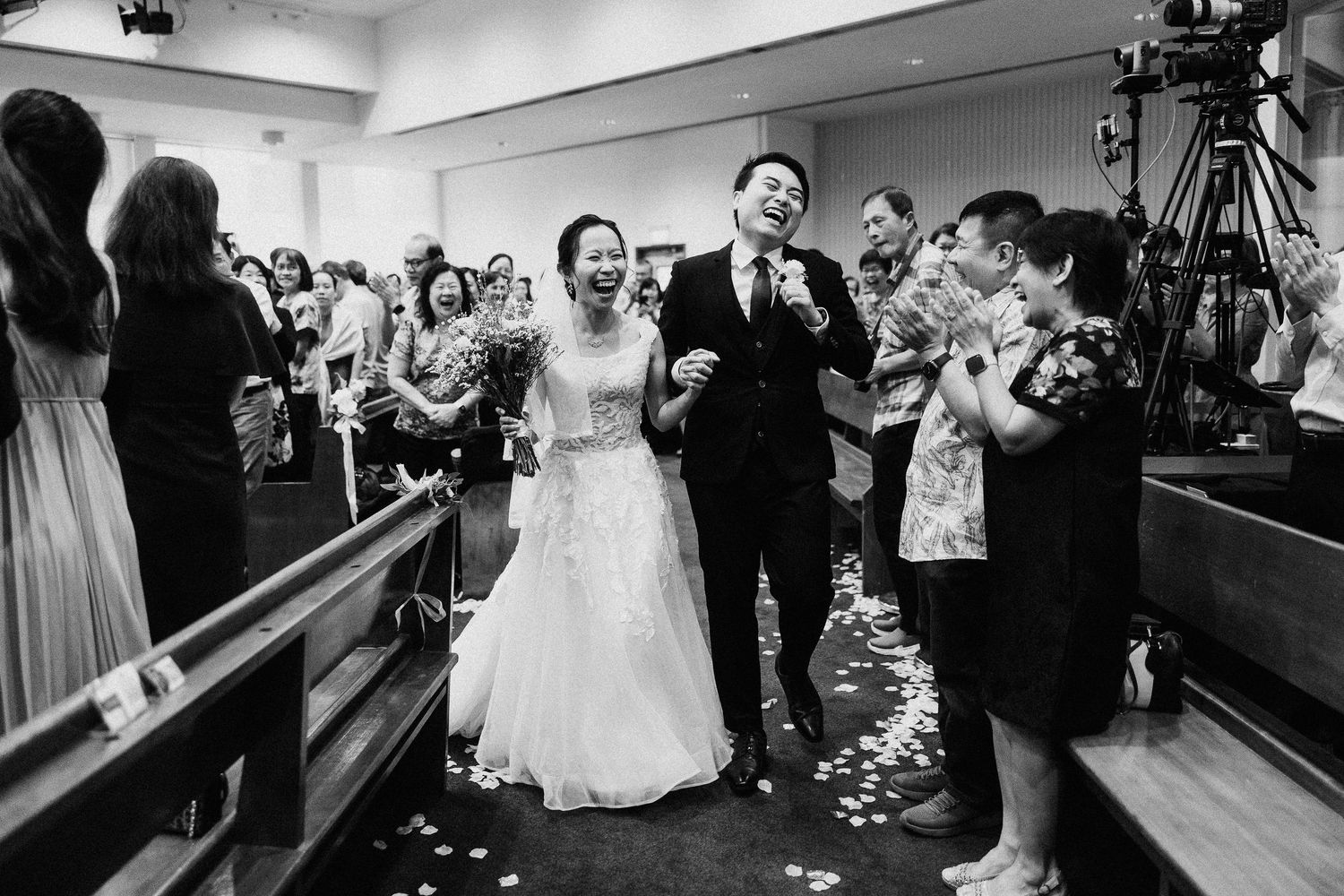 Black and white wedding reception scene with people celebrating on dance floor.