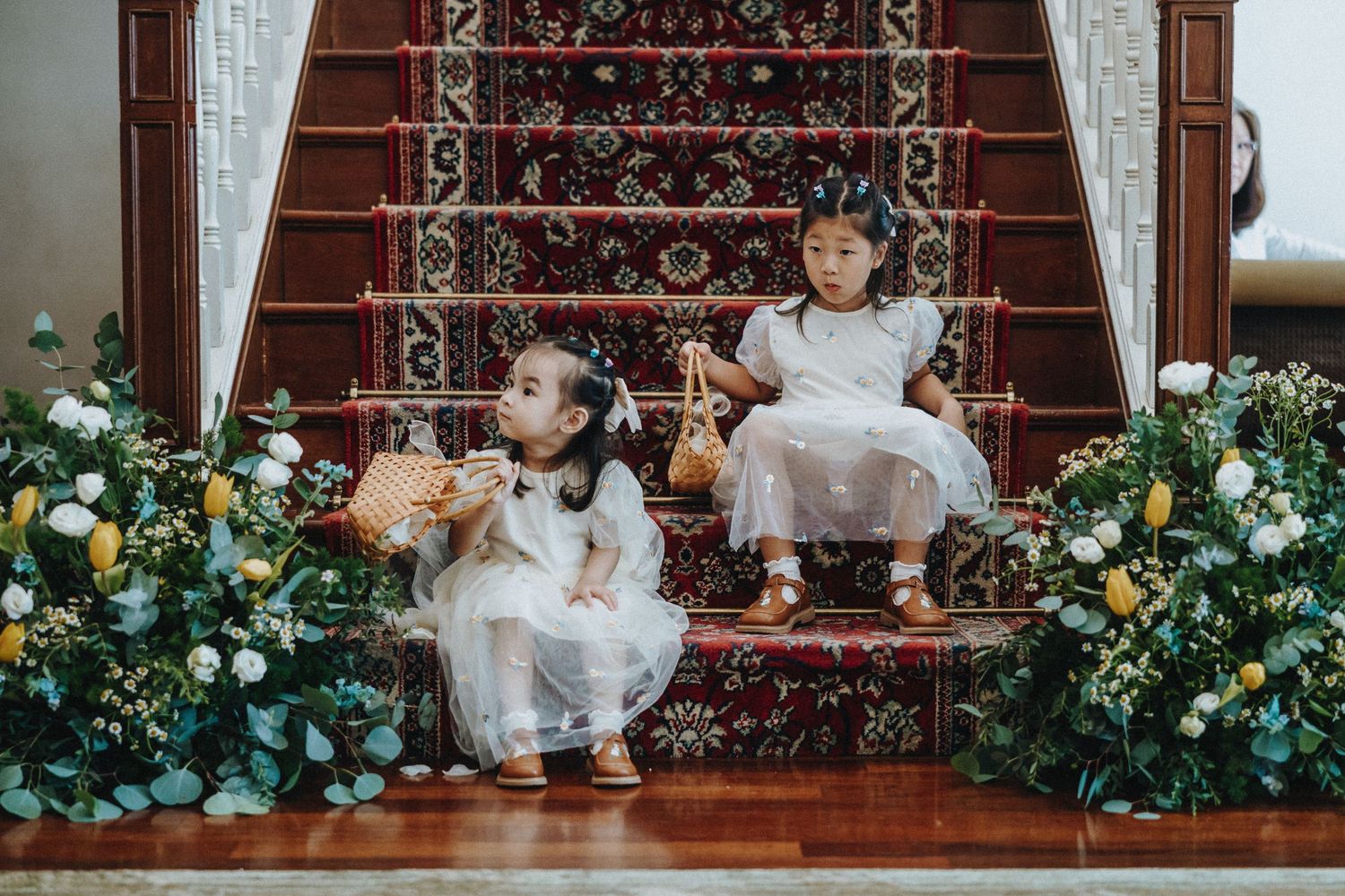 Beautiful floral arrangements adorn a wooden staircase during an elegant indoor wedding ceremony.