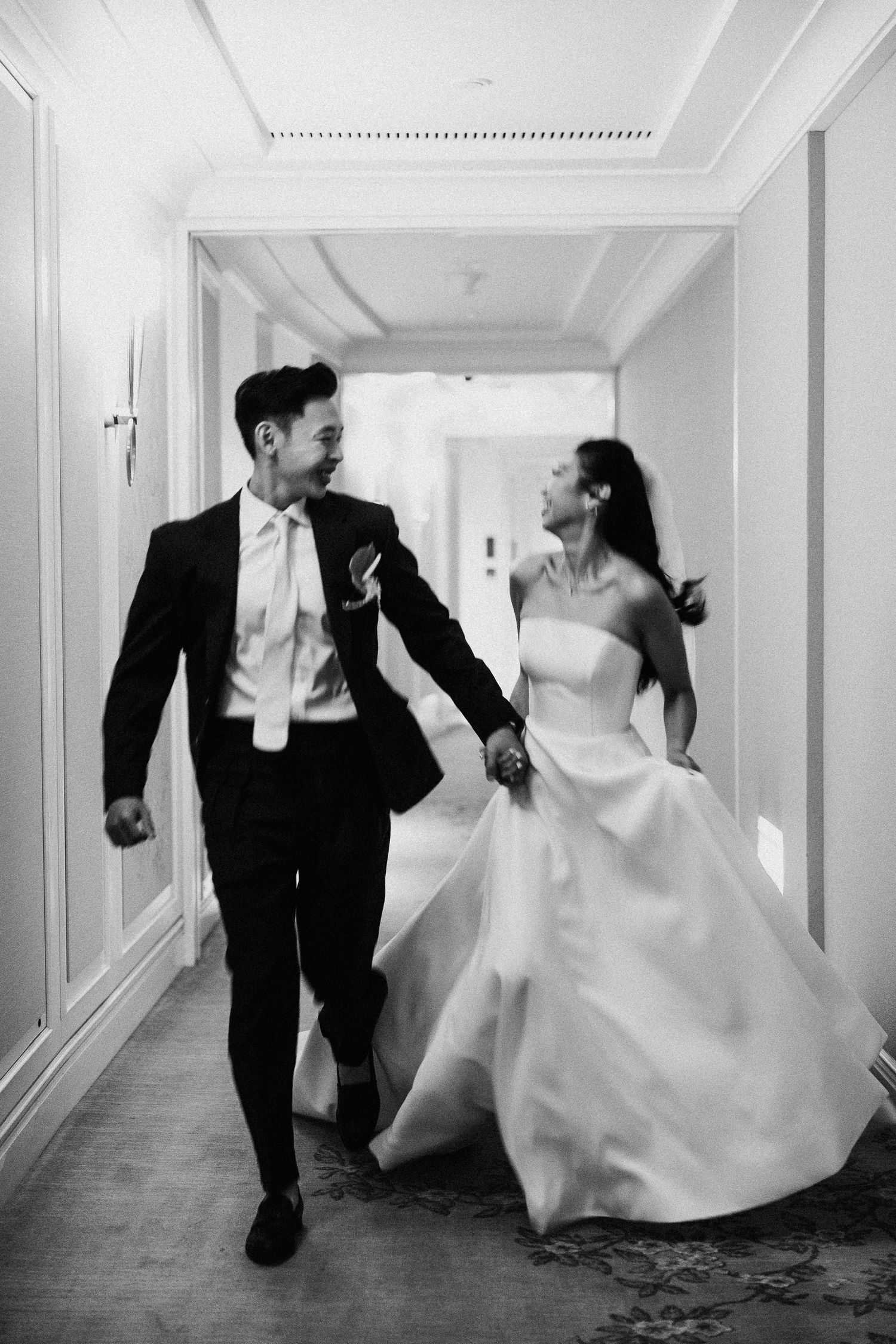 A sequence showing a bride and groom racing and laughing through a bright hotel corridor.