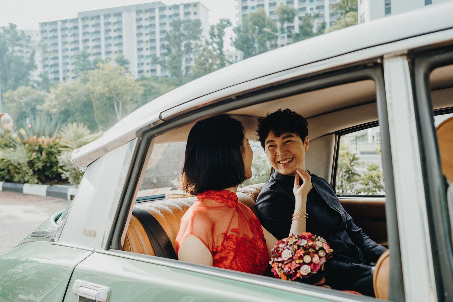 Wedding party arriving in white cars outside modern apartment buildings.