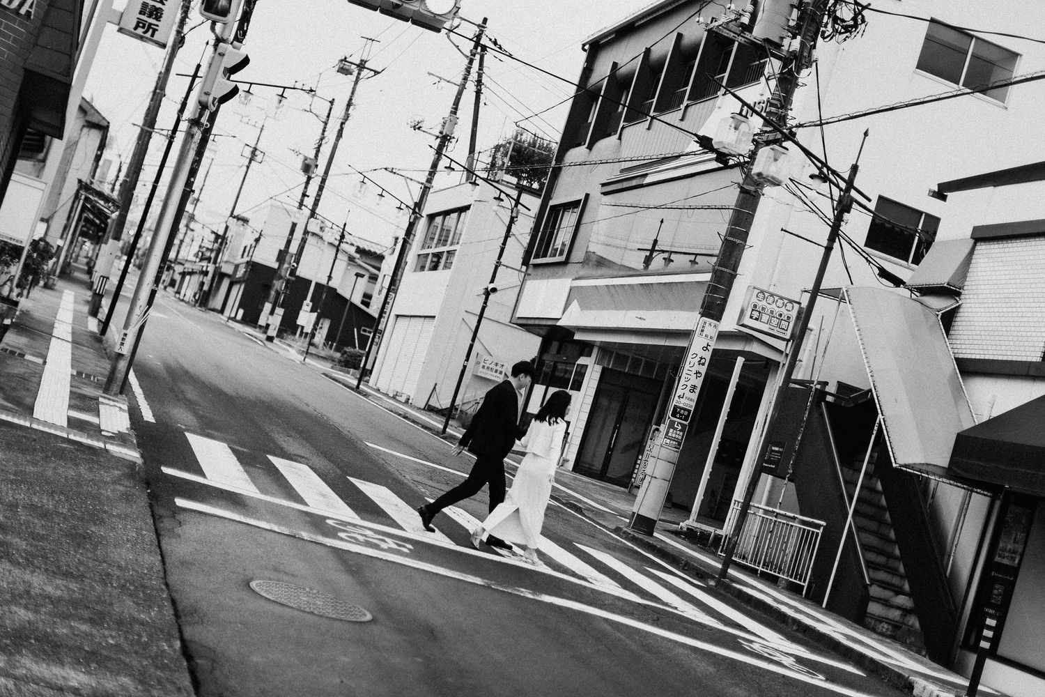 Urban Japanese street scene with power lines and buildings in black and white.