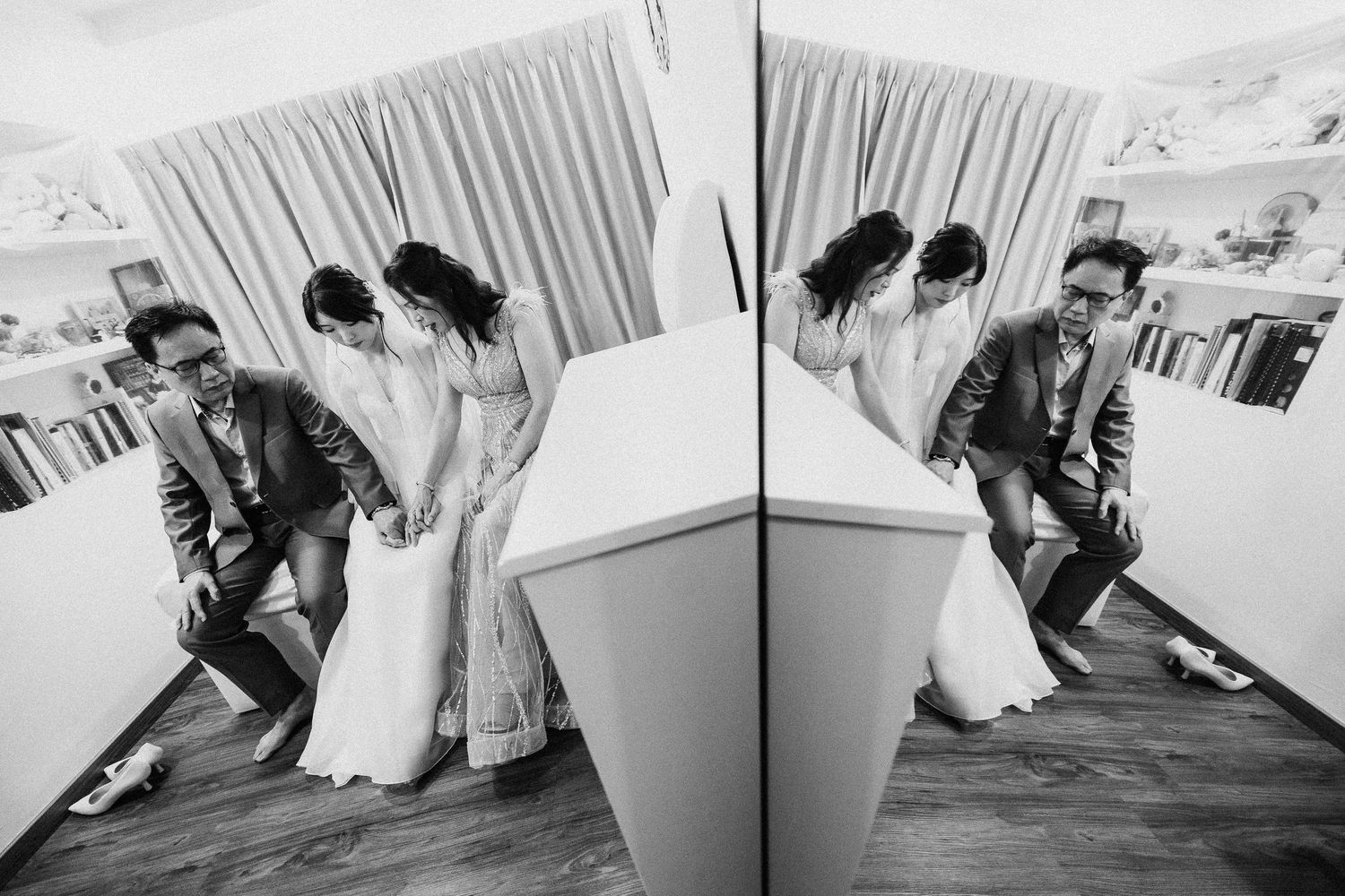 Black and white photo of a wedding party dancing and posing together playfully on a dance floor with mirrored reflection.