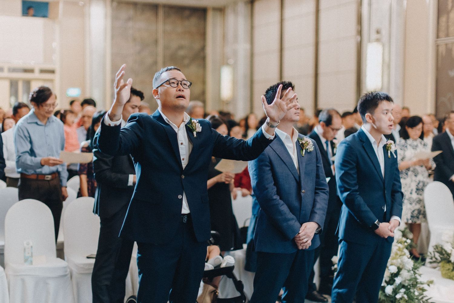Wedding guests in formal attire celebrating enthusiastically during a reception.