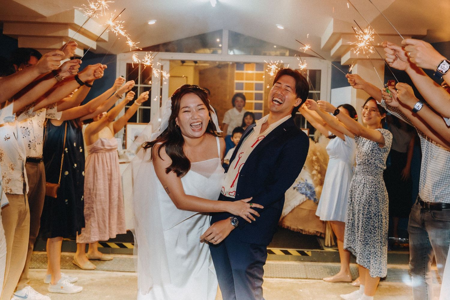 Wedding guests dance and celebrate on a wooden dance floor under warm lighting during the reception festivities.