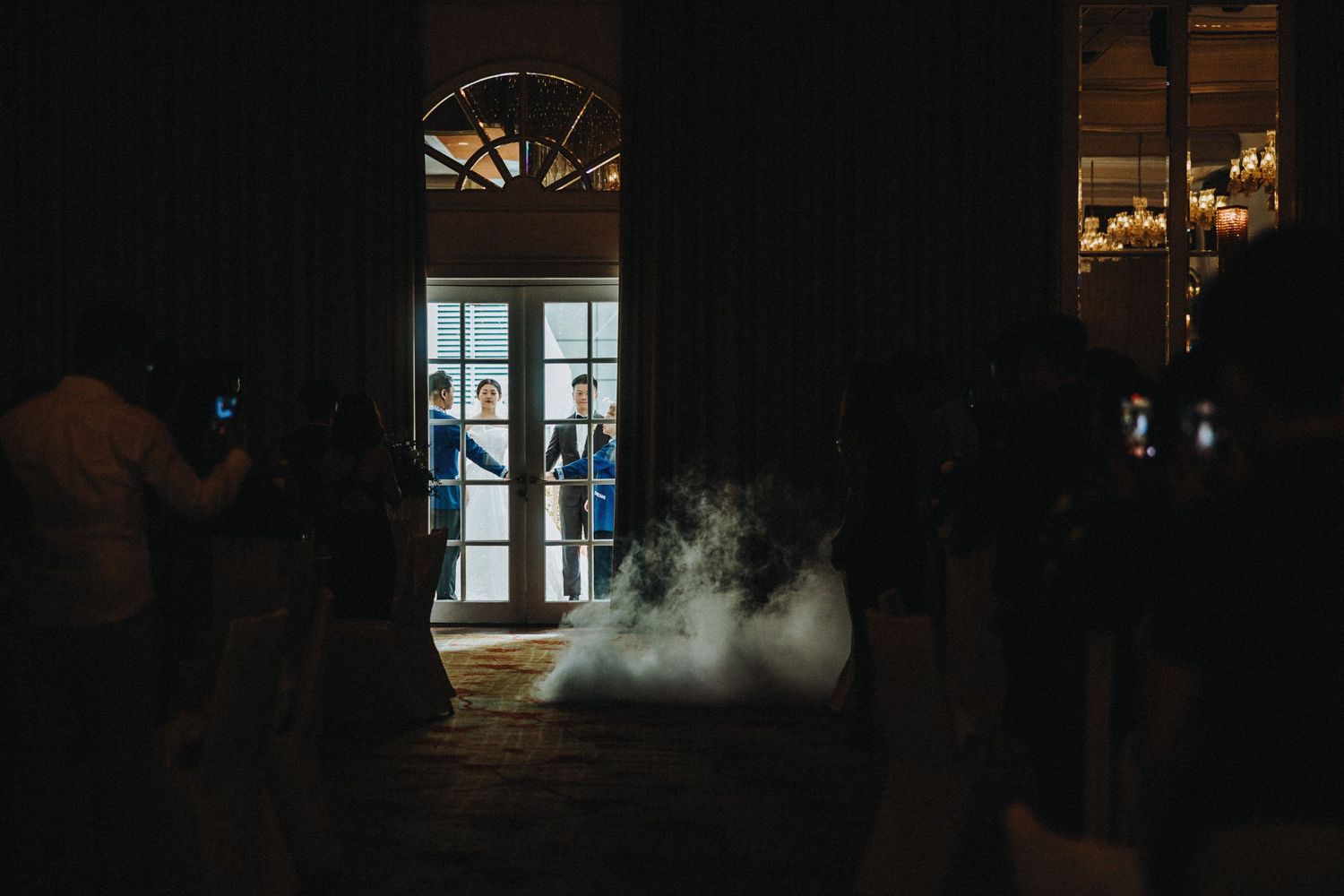 Atmospheric evening wedding venue with light filtering through windows creating a romantic silhouette.