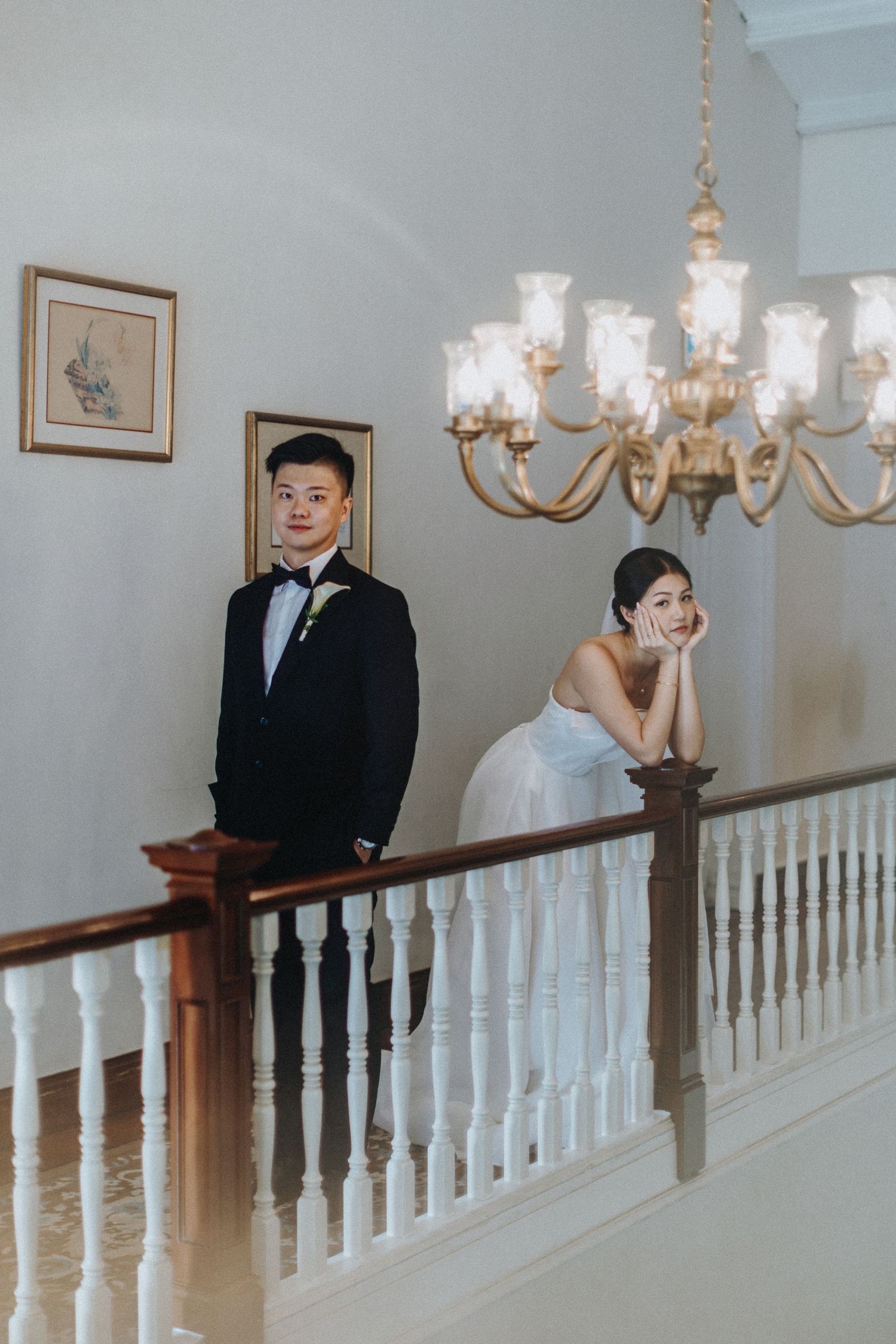 A grand staircase with white balusters and an elegant chandelier in an indoor setting.
