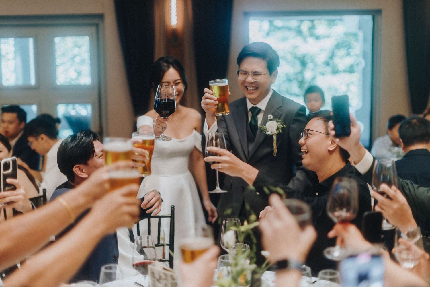Wedding reception guests raise their glasses in a celebratory toast during the party.