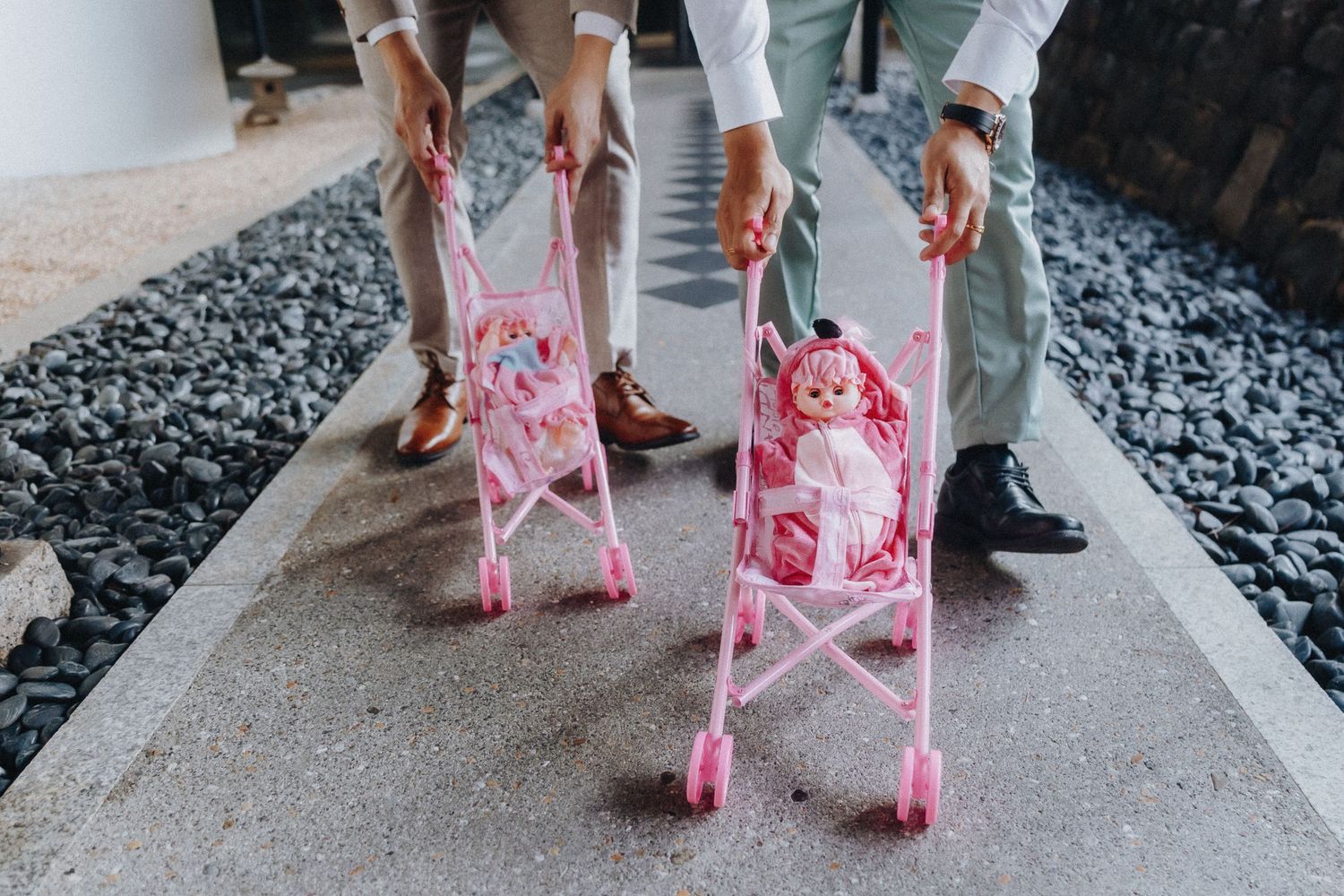 Wedding party members wearing pink and white outfits walk together on a stone pathway.