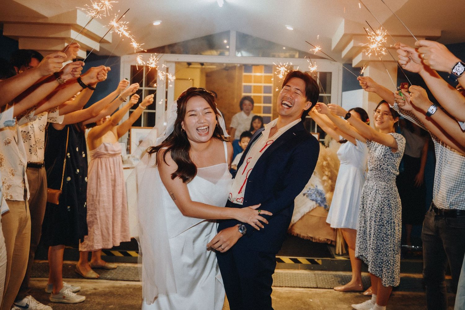 Wedding celebration with guests dancing and celebrating under warm lighting.